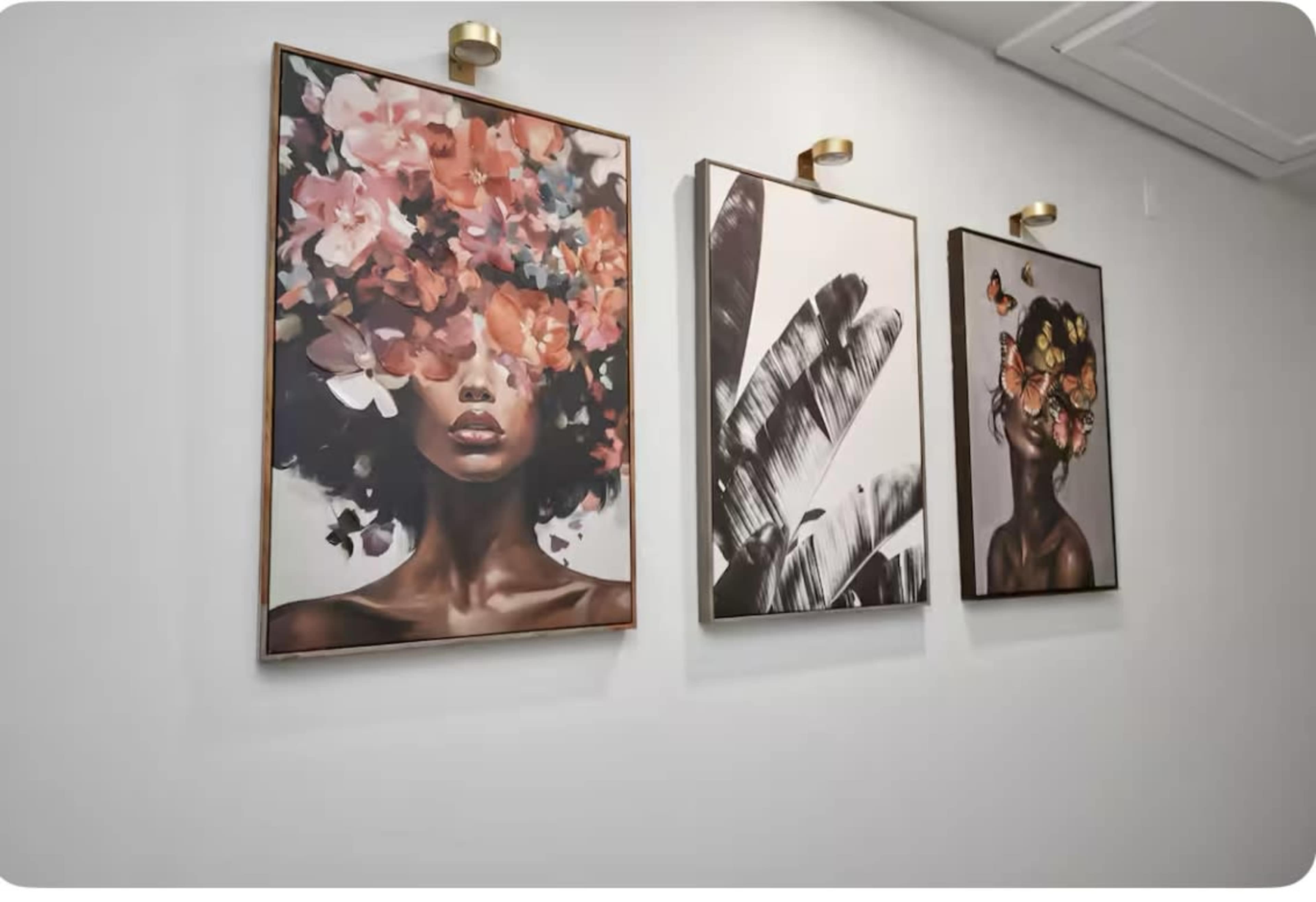 Three framed art pieces featuring floral and butterfly designs hang on a white wall.
