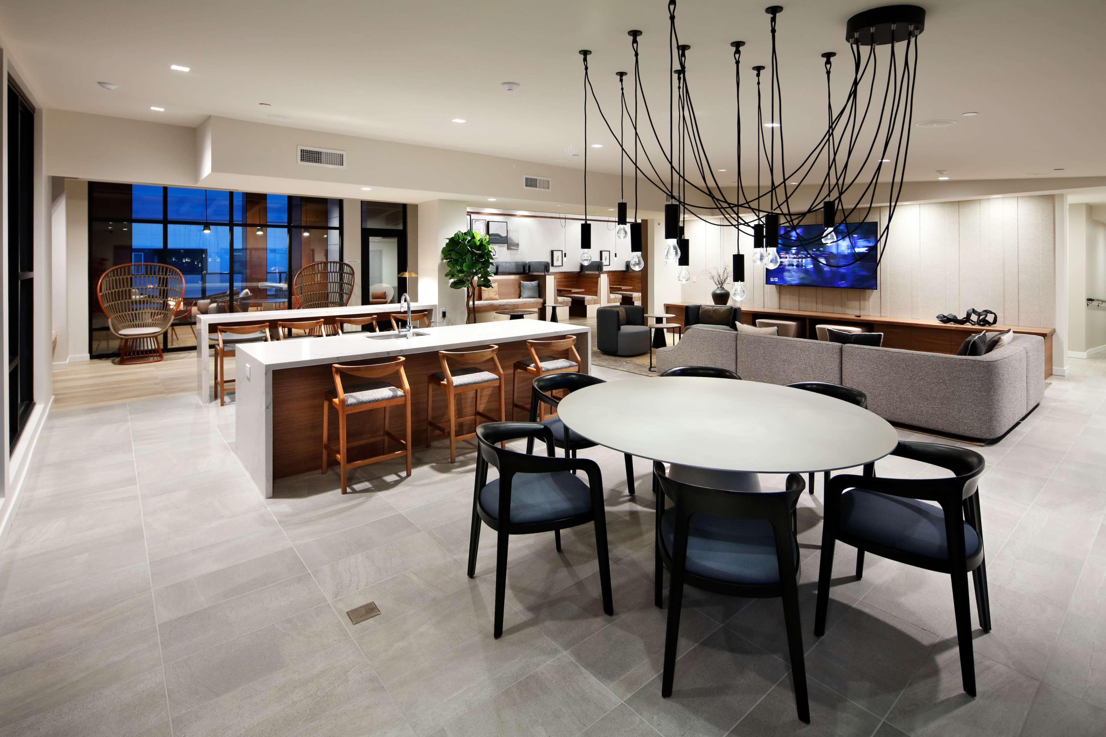 A modern open-concept living space with a dining area, lounge seating, and large windows letting in natural light.