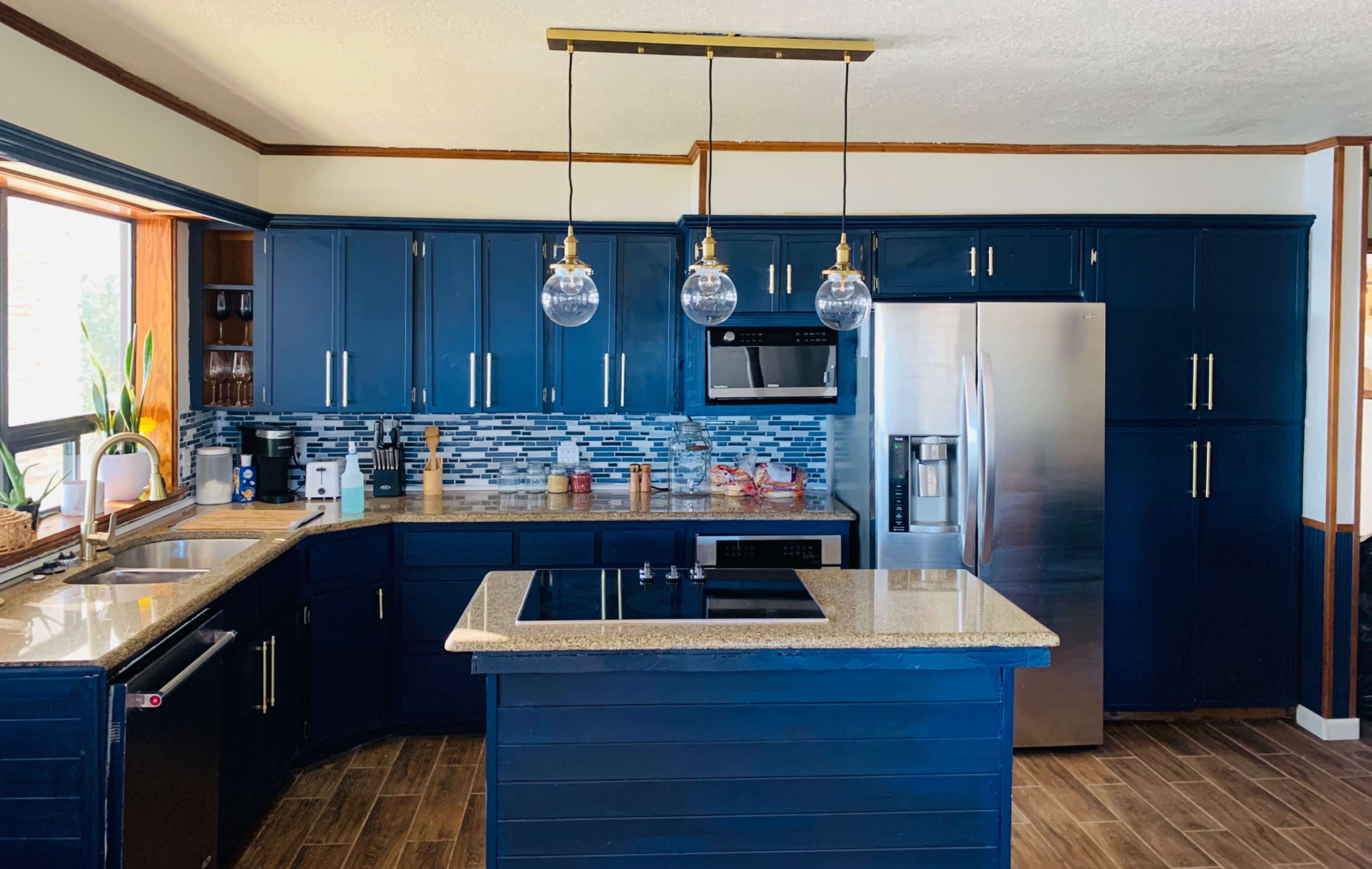 The kitchen features navy blue cabinets, a granite countertop, and modern appliances, including a stainless steel refrigerator and an electric cooktop.