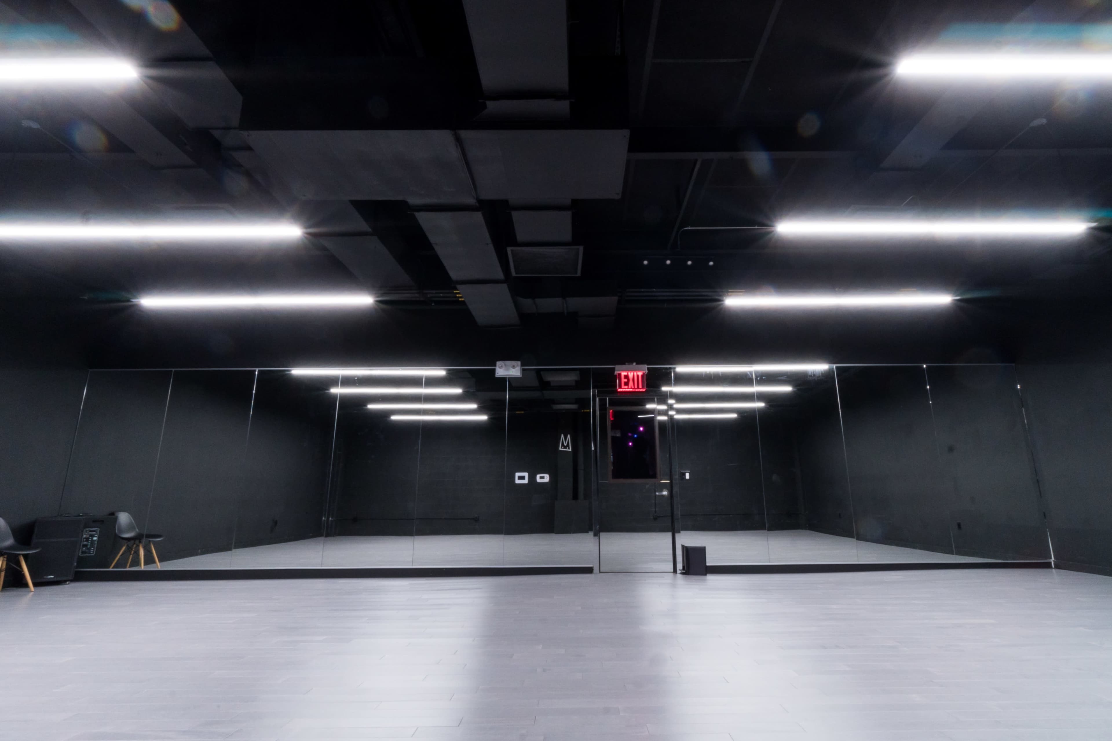 An empty black-walled studio space with LED lights and a large mirrored wall.