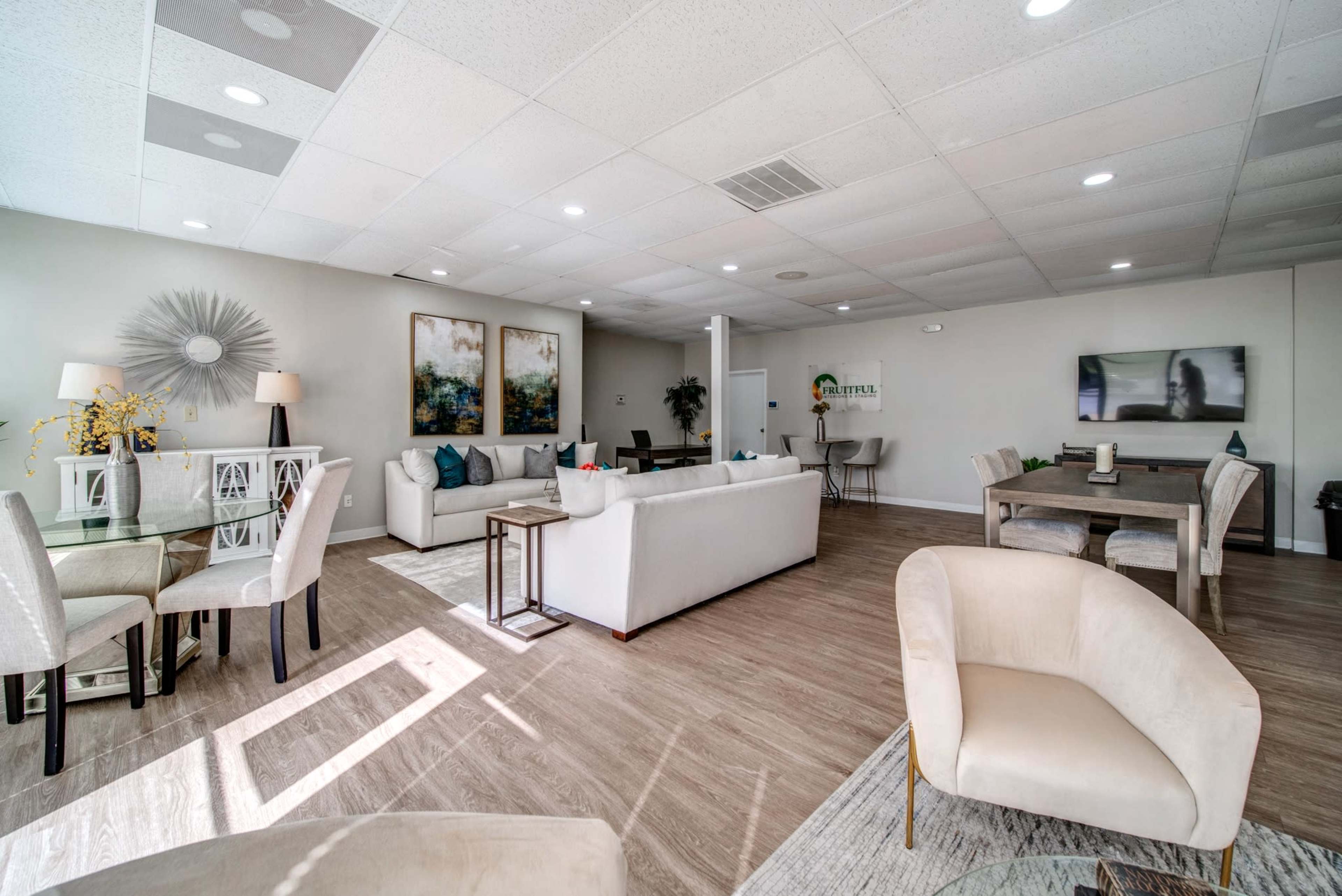 A modern, spacious lounge area with neutral-colored furniture, decorative art pieces on the walls, and ample natural light illuminating the space.