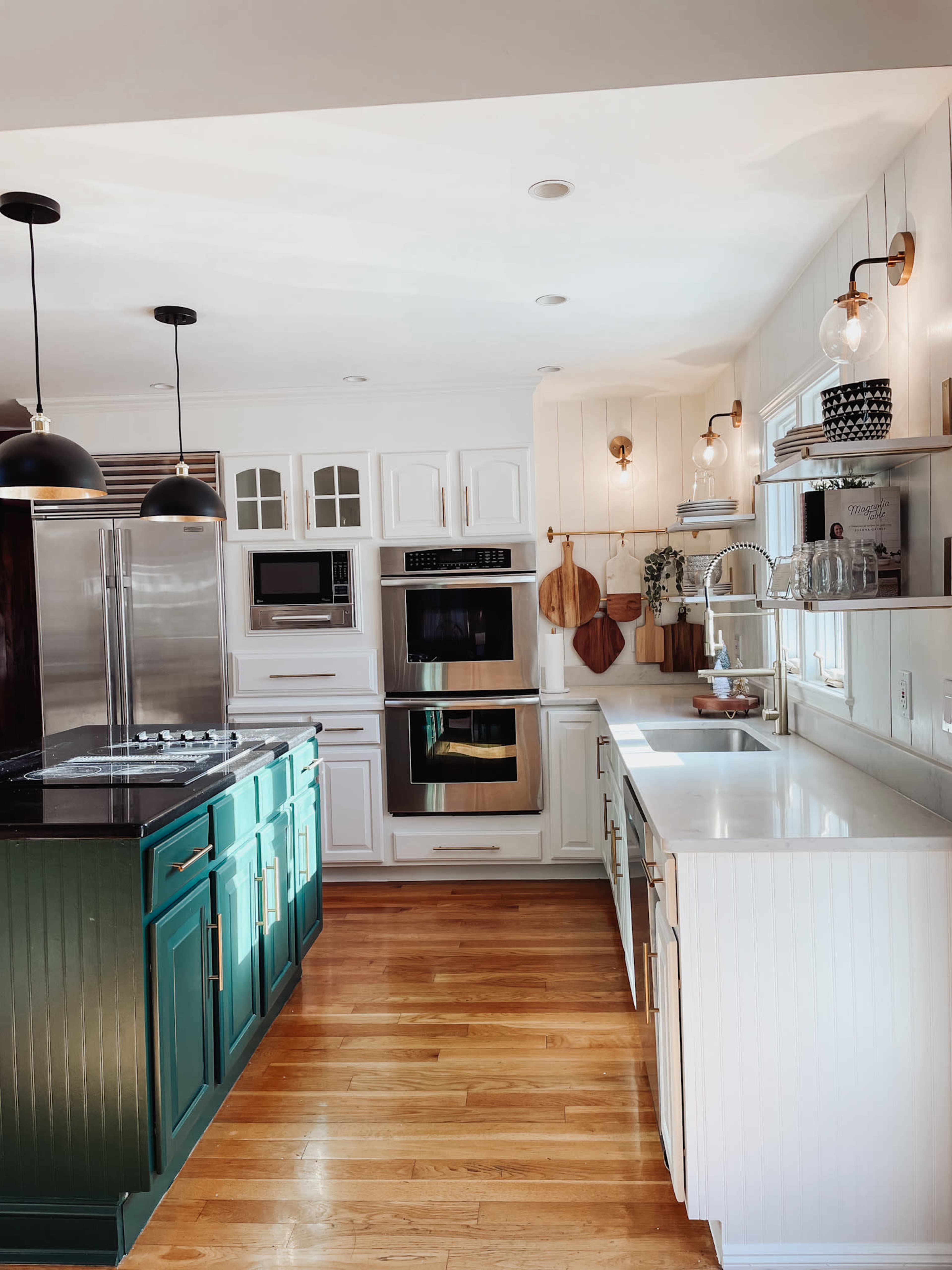 The kitchen features white cabinetry, green lower cabinets, stainless steel appliances, and a light wood floor.