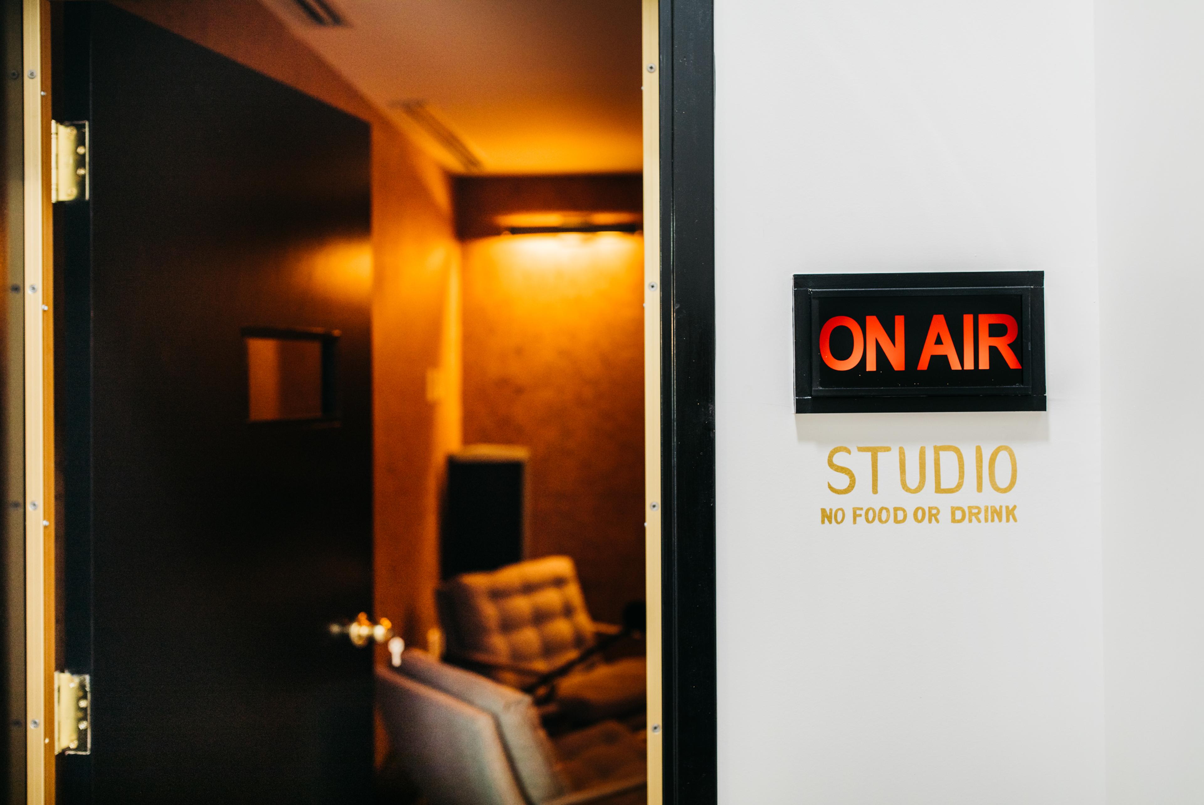 A sign on a door indicates an "ON AIR" studio, featuring a warning against bringing food or drink inside.