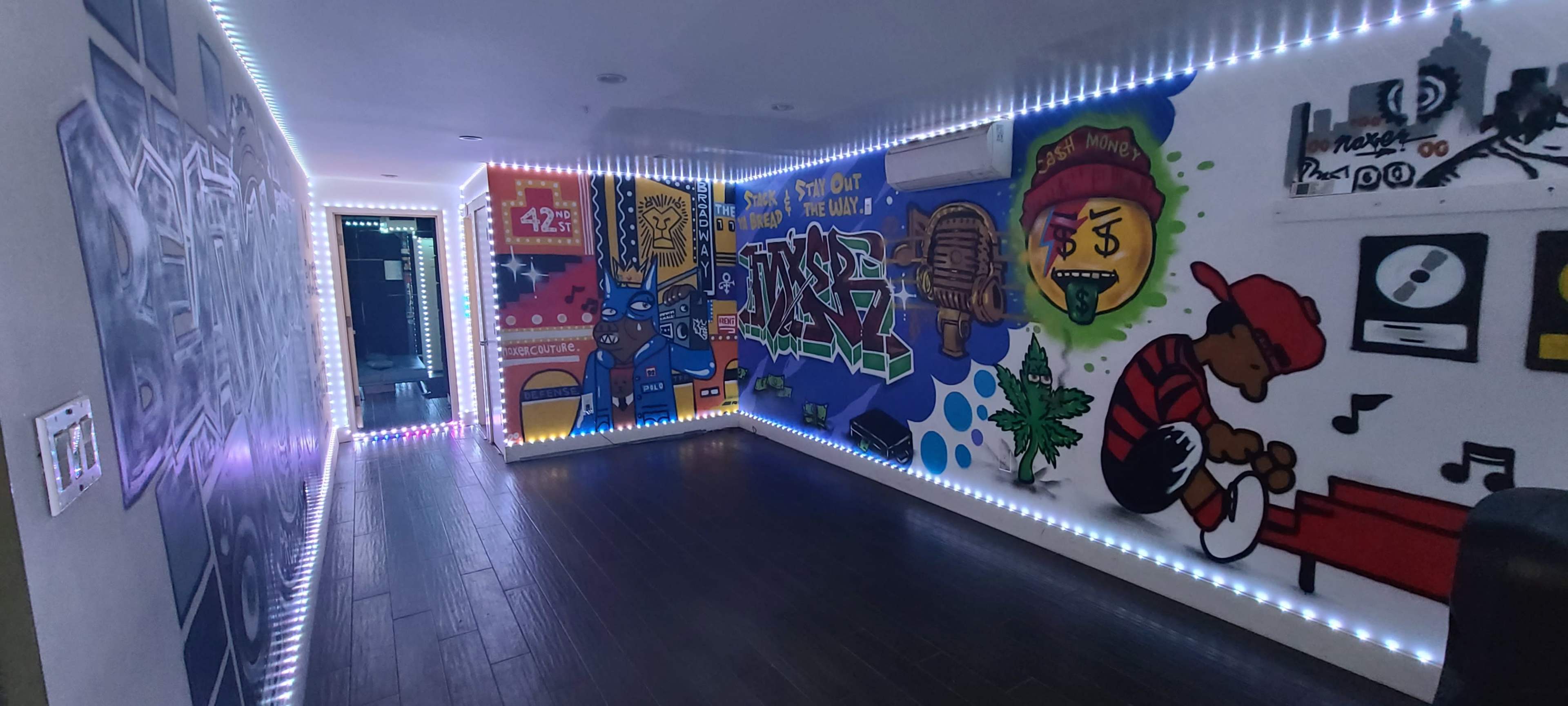 A hallway decorated with vibrant murals and illuminated by LED strip lights along the walls.