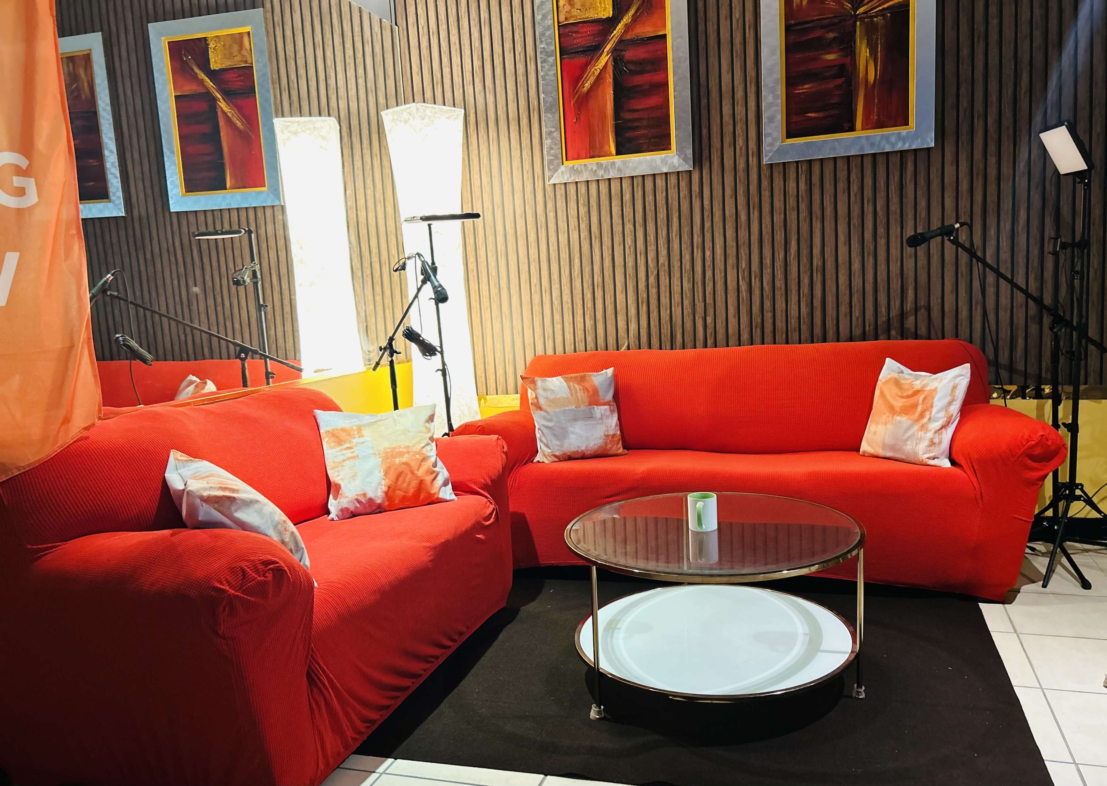 A cozy seating area with two red sofas, a round glass coffee table, and artistic wall decorations.