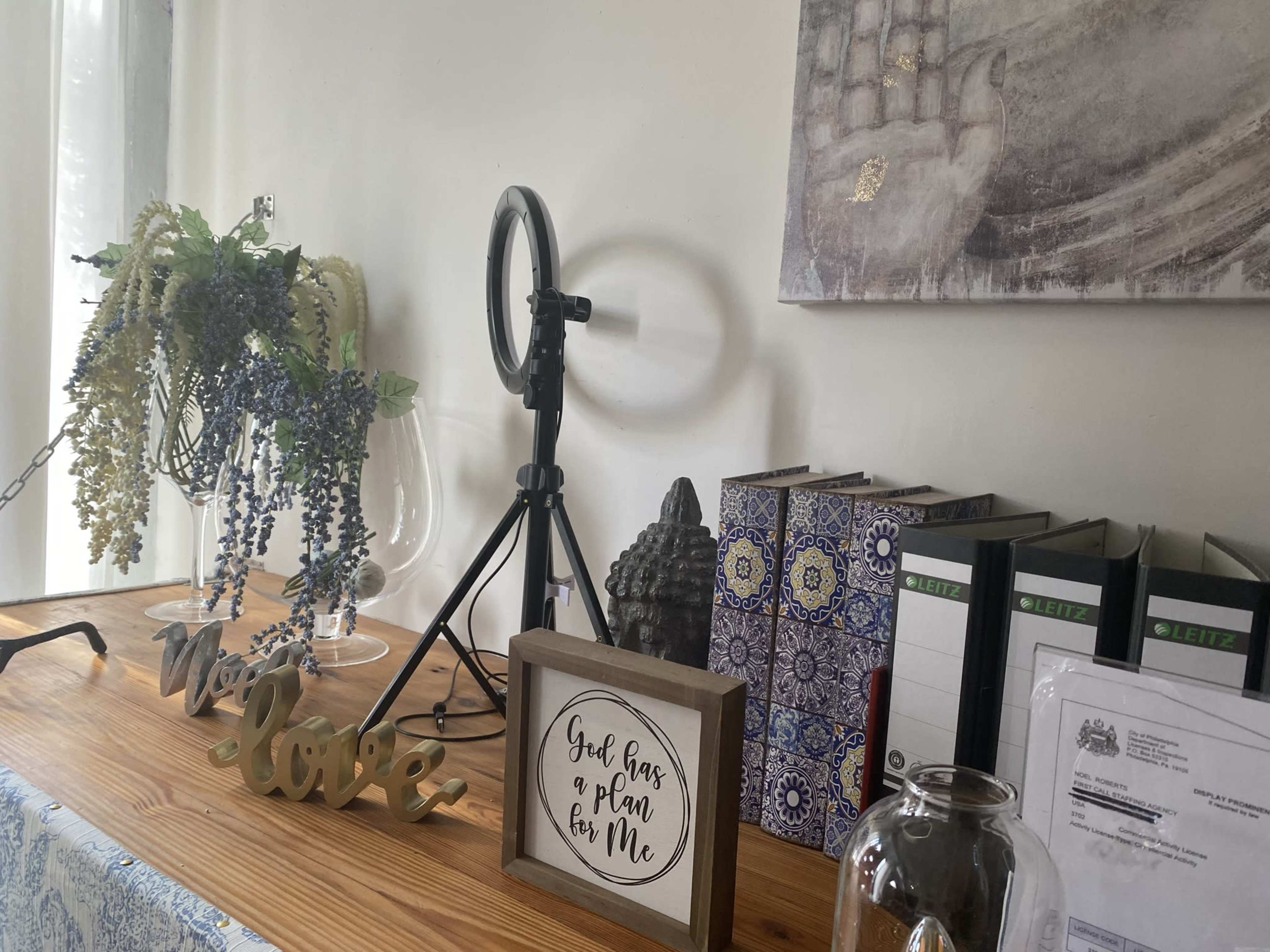 A wooden table adorned with decorative items, including a framed quote, a small statue, books, and flowers.