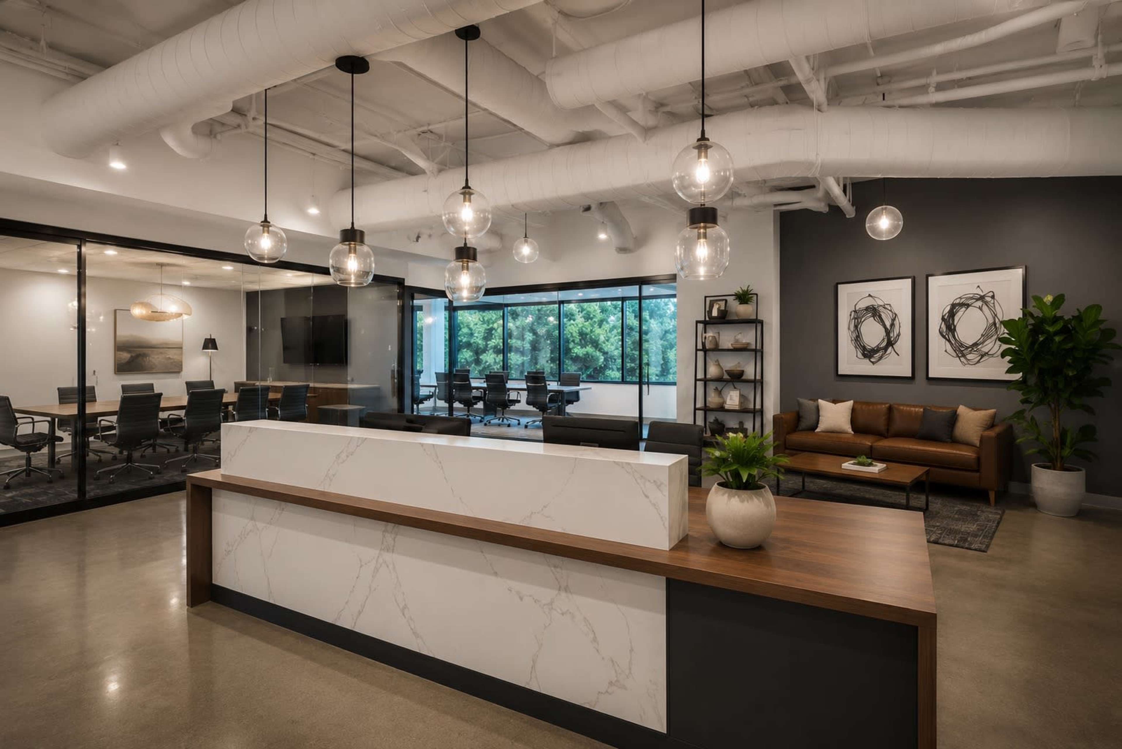 The image shows a modern office reception area with a marble-fronted desk, hanging light fixtures, and a seating area that includes a brown sofa, framed artwork, and a large window overlooking greenery.