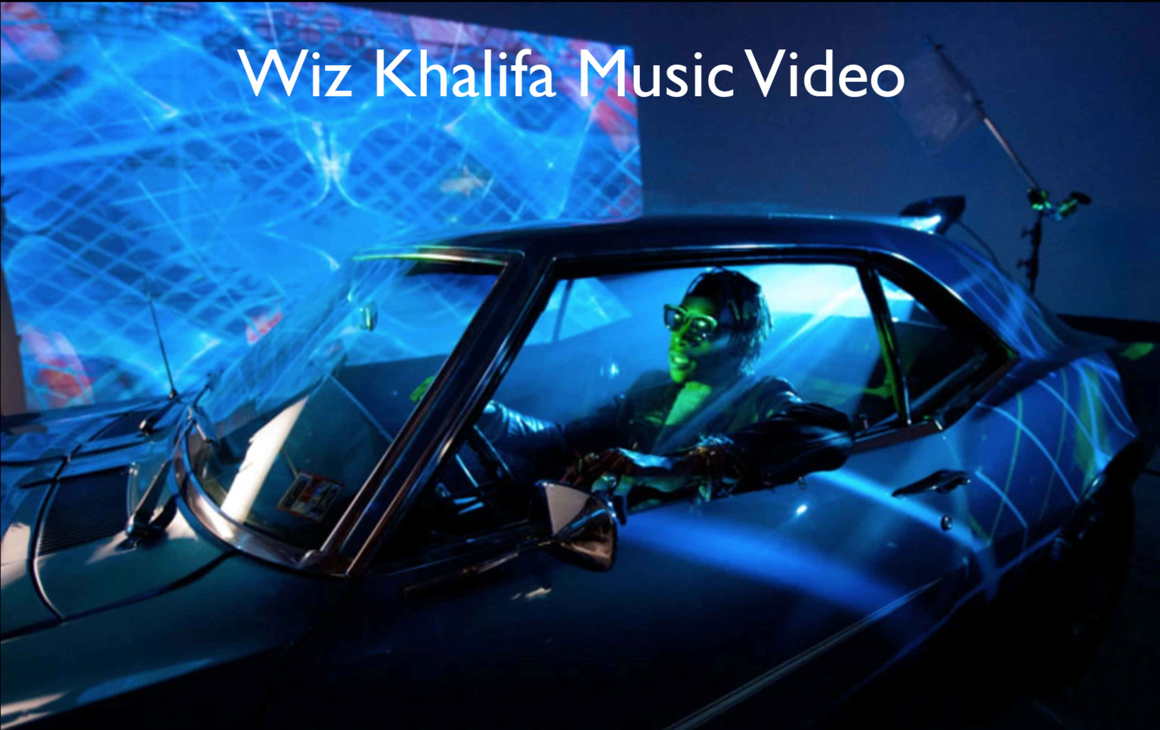 A person is sitting in a car with vibrant blue lighting and digital visuals projected behind them.