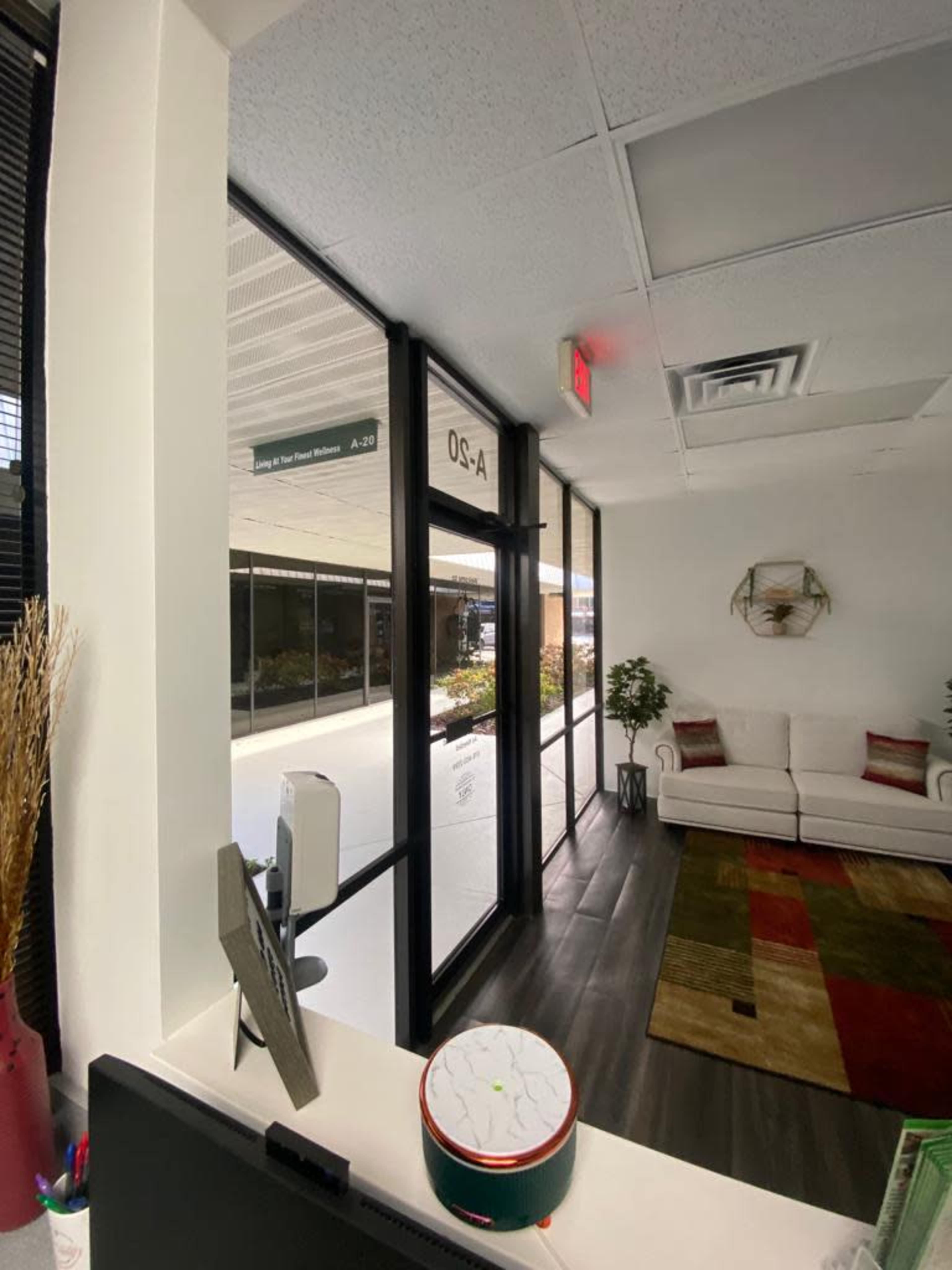 The image shows a reception area with a visible seating area, a door leading outside, and a decorative rug on the floor.