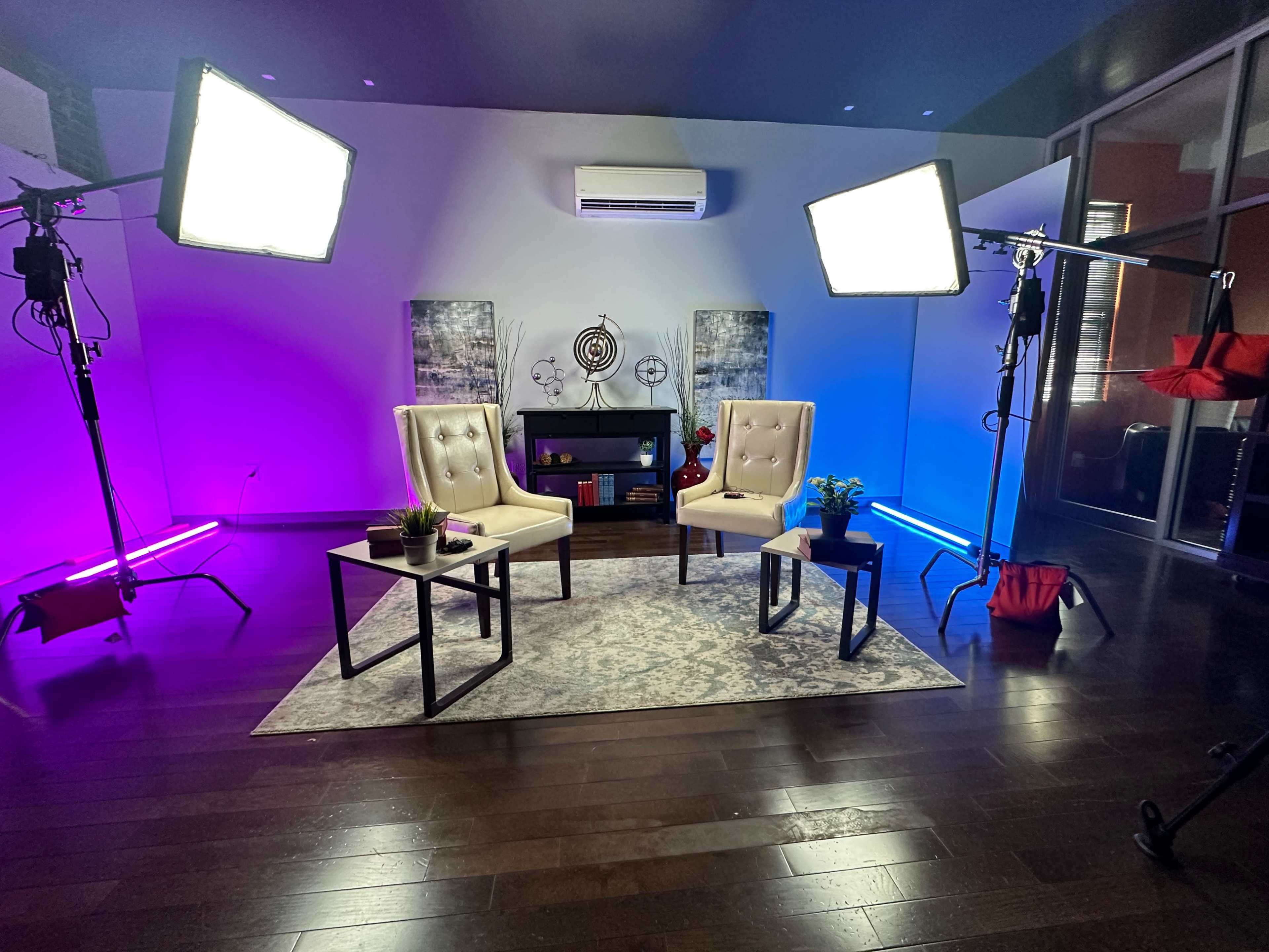 A well-lit interview setup with two chairs, a small table, and colorful lighting in a modern interior space.