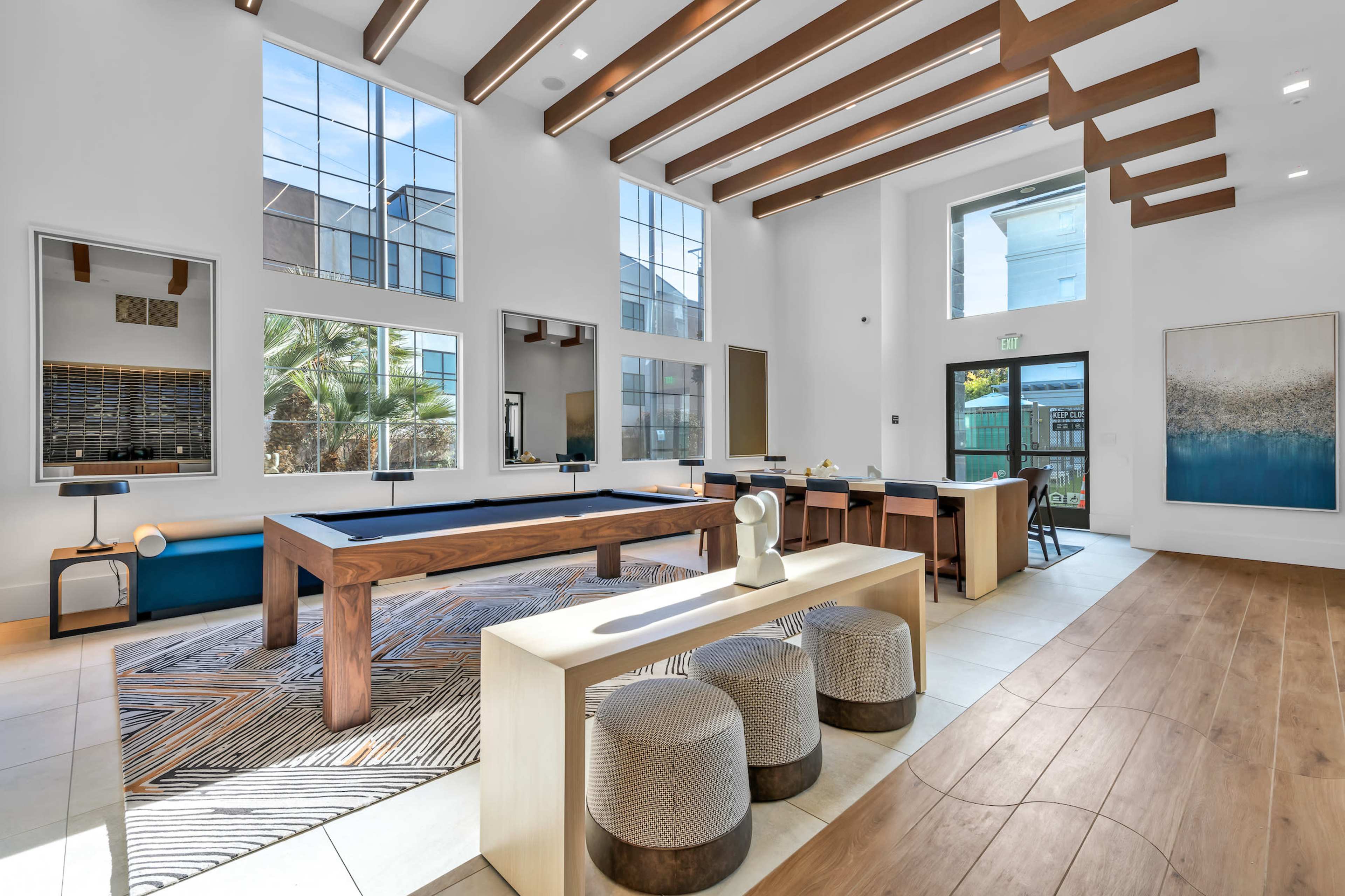 A modern communal lounge with a billiard table, seating area, and large windows letting in natural light.
