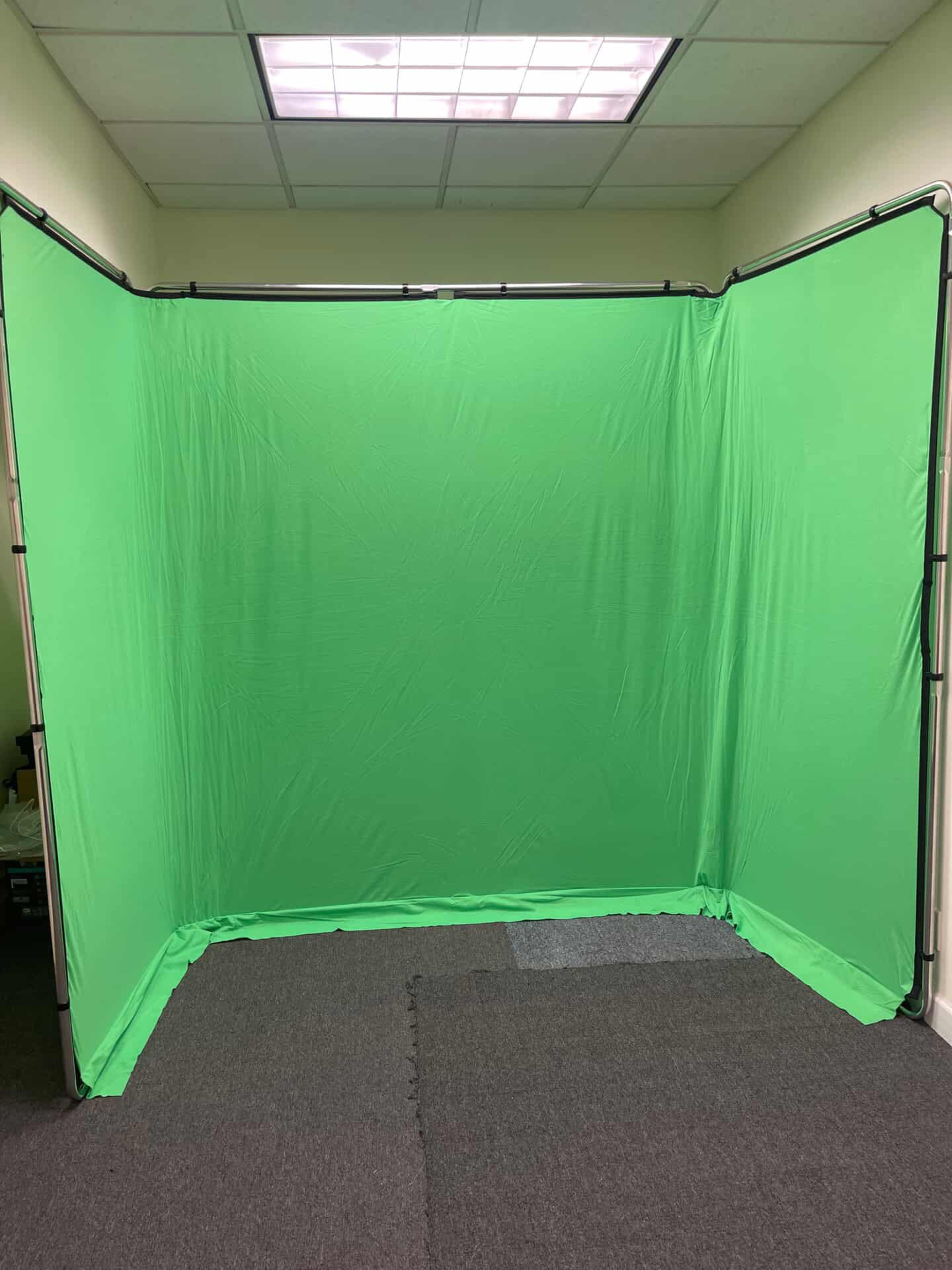 A green screen setup is displayed in a room with gray carpeting.