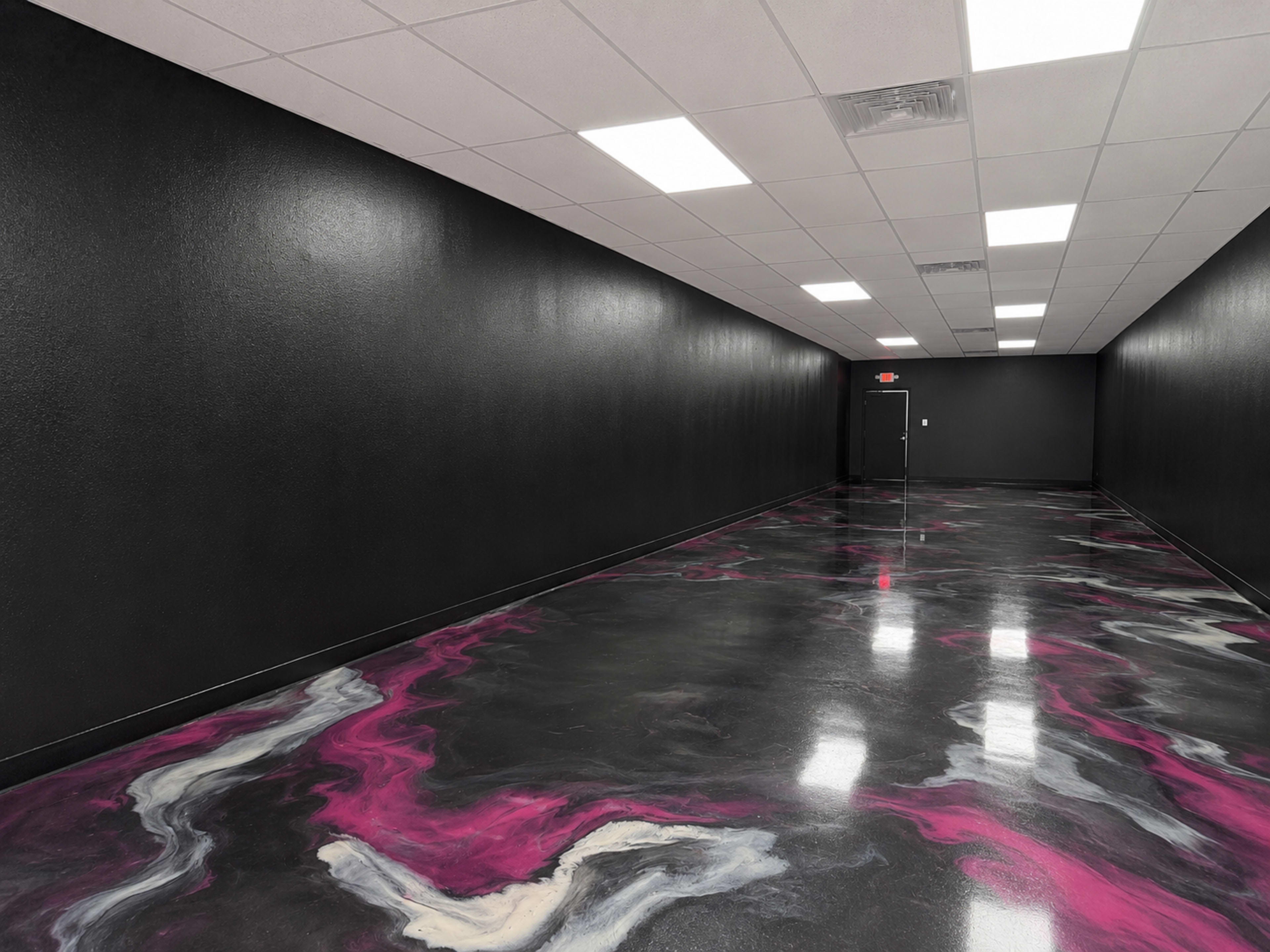 A long, narrow corridor features glossy black walls and a vibrant, marbled floor with swirls of pink and white.