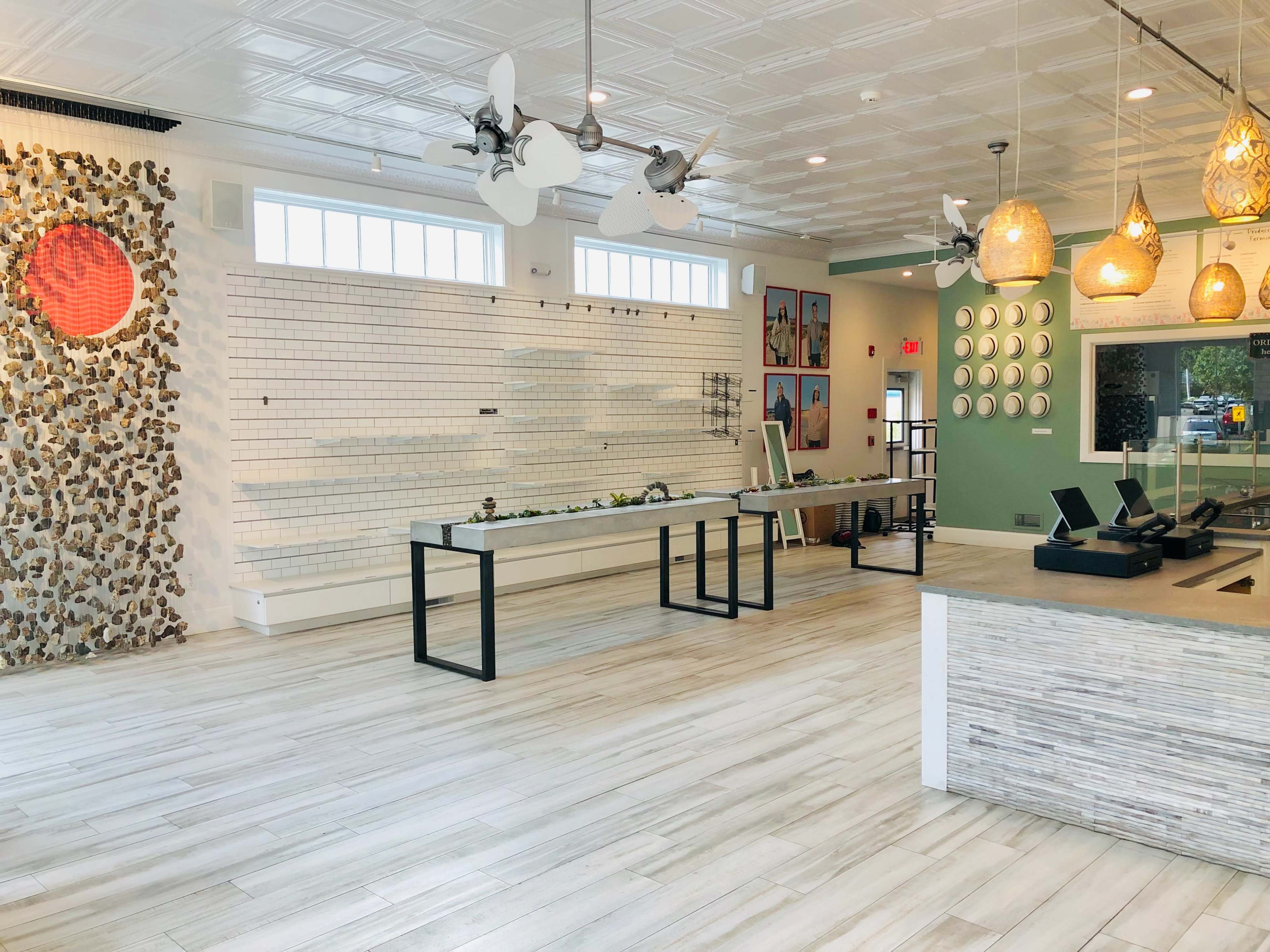 An empty, modern cafe interior with a central service counter, decorative wall art, and minimalist furnishings.