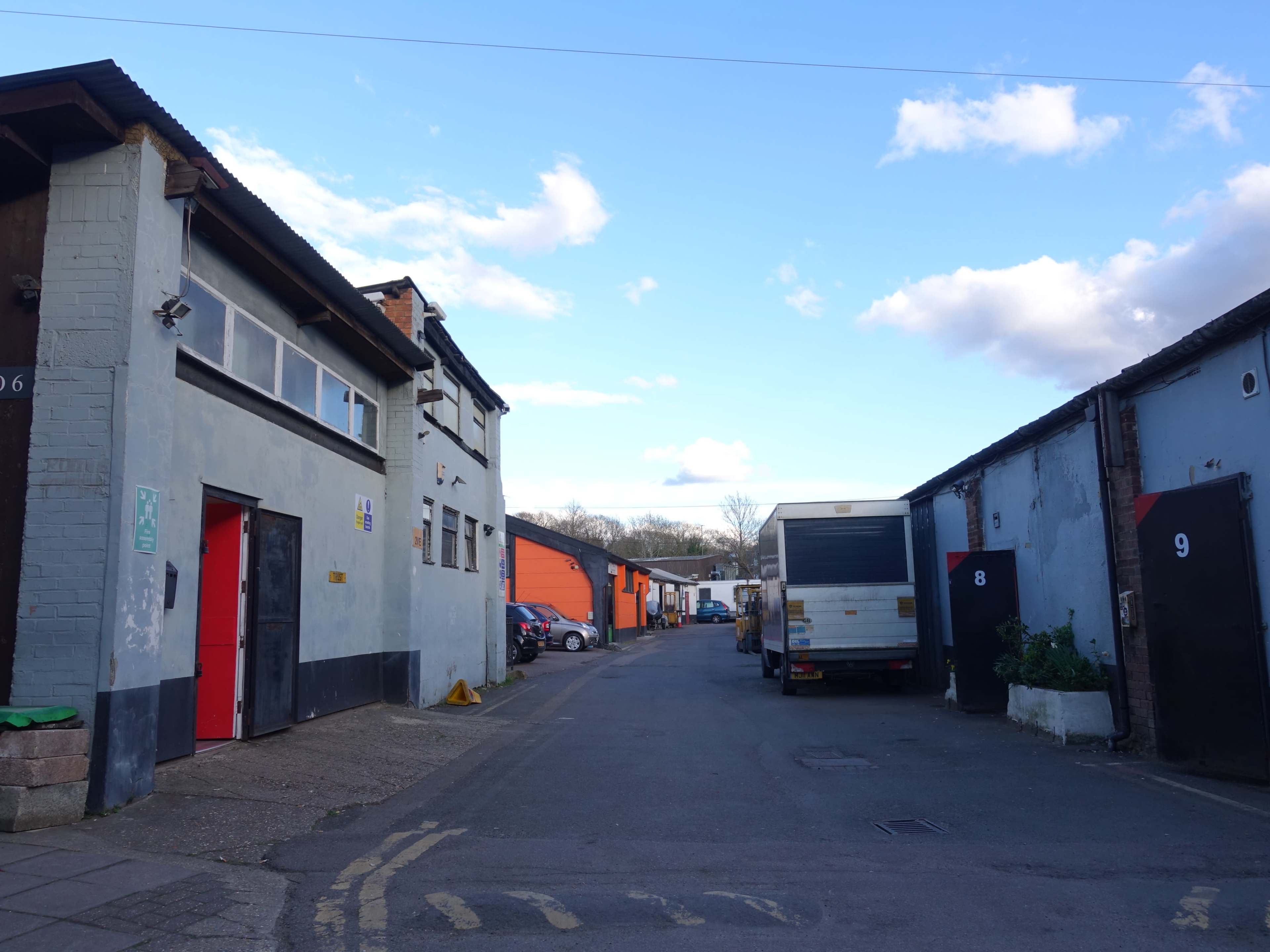 The image shows a narrow alleyway between buildings, with parked cars and a white delivery truck present in the scene.