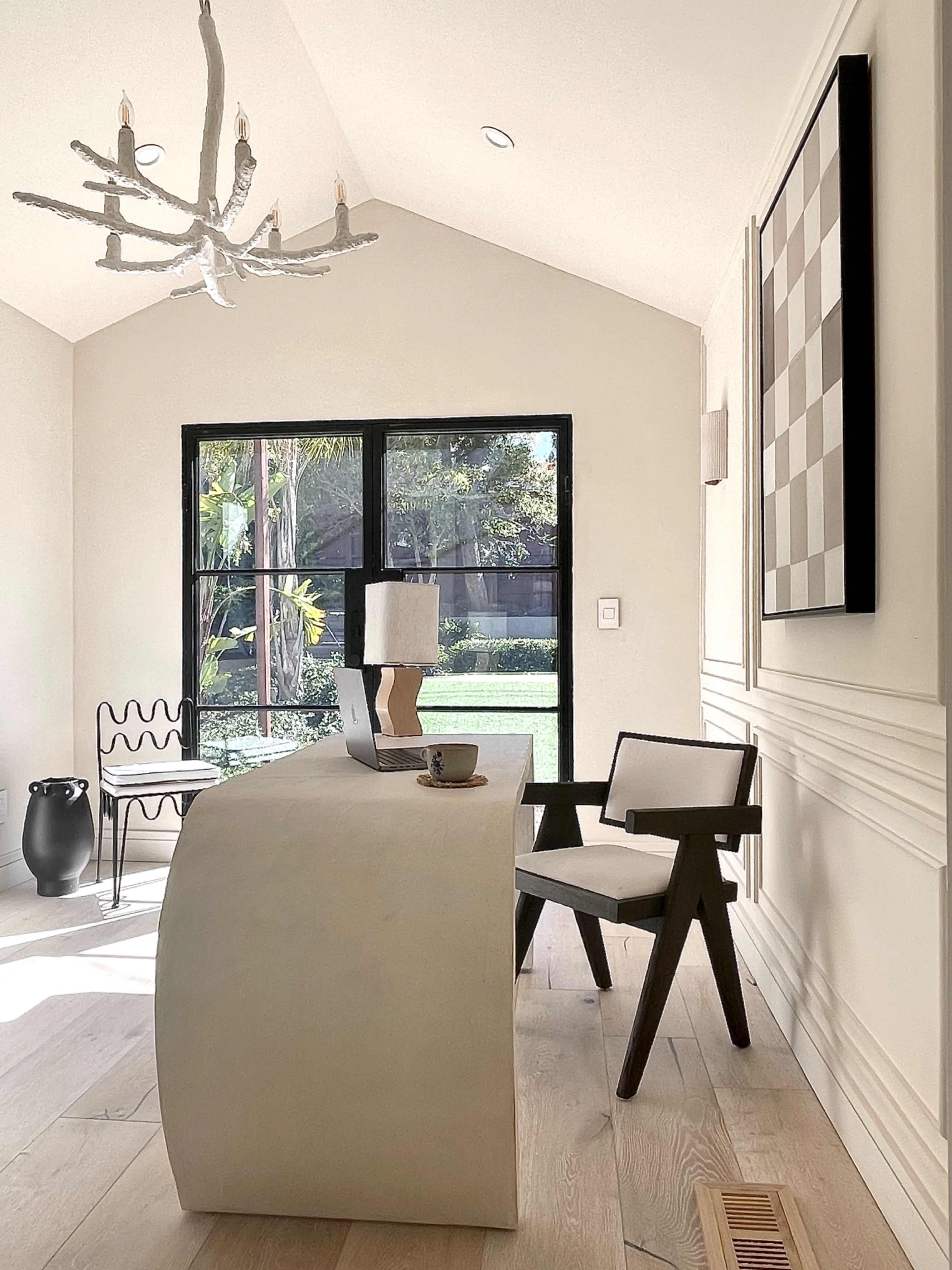 A minimalistic home office features a curved desk, a modern chair, and a large window overlooking a garden.
