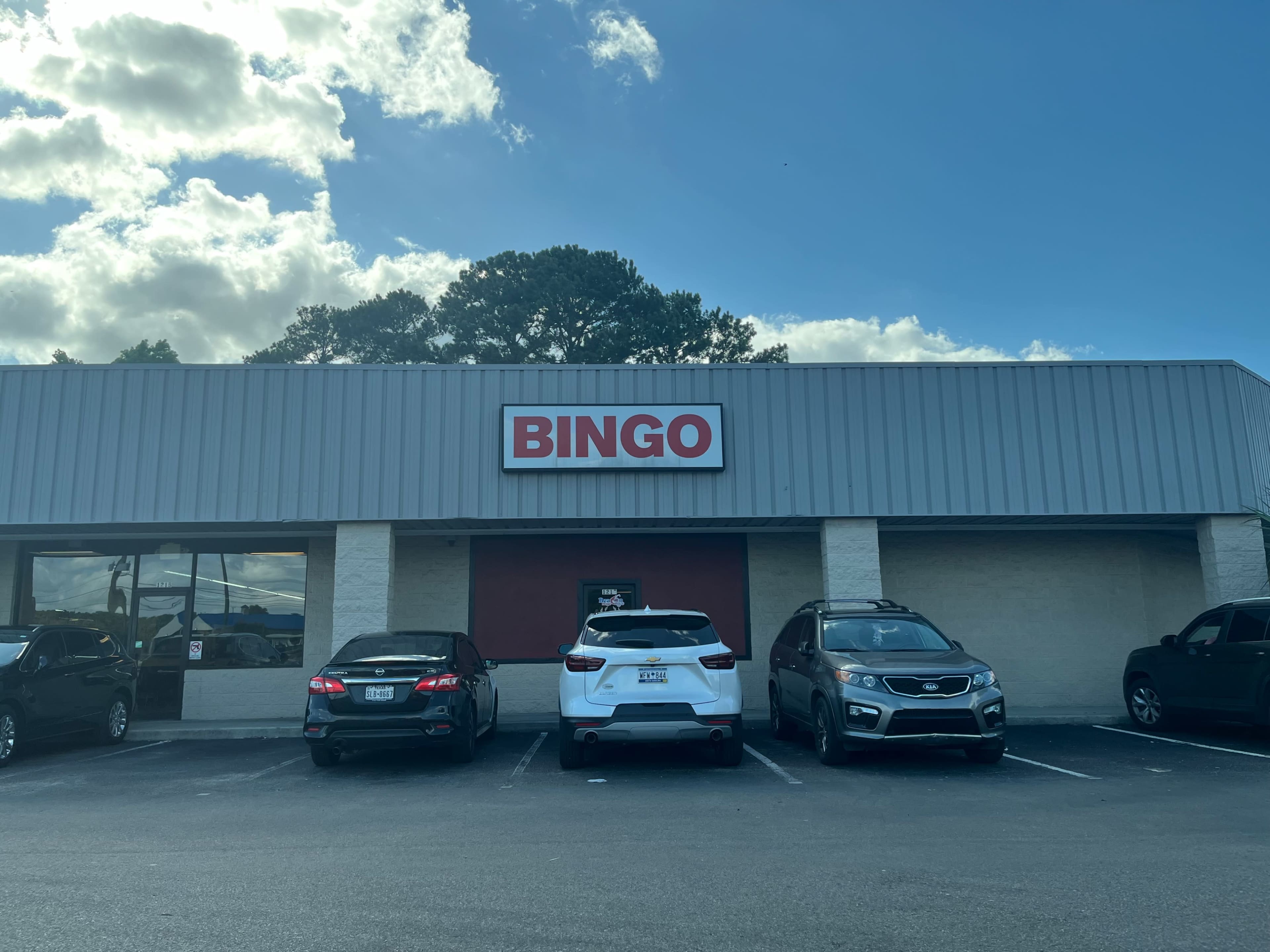 A building with a sign that reads "BINGO" and several parked cars in front.
