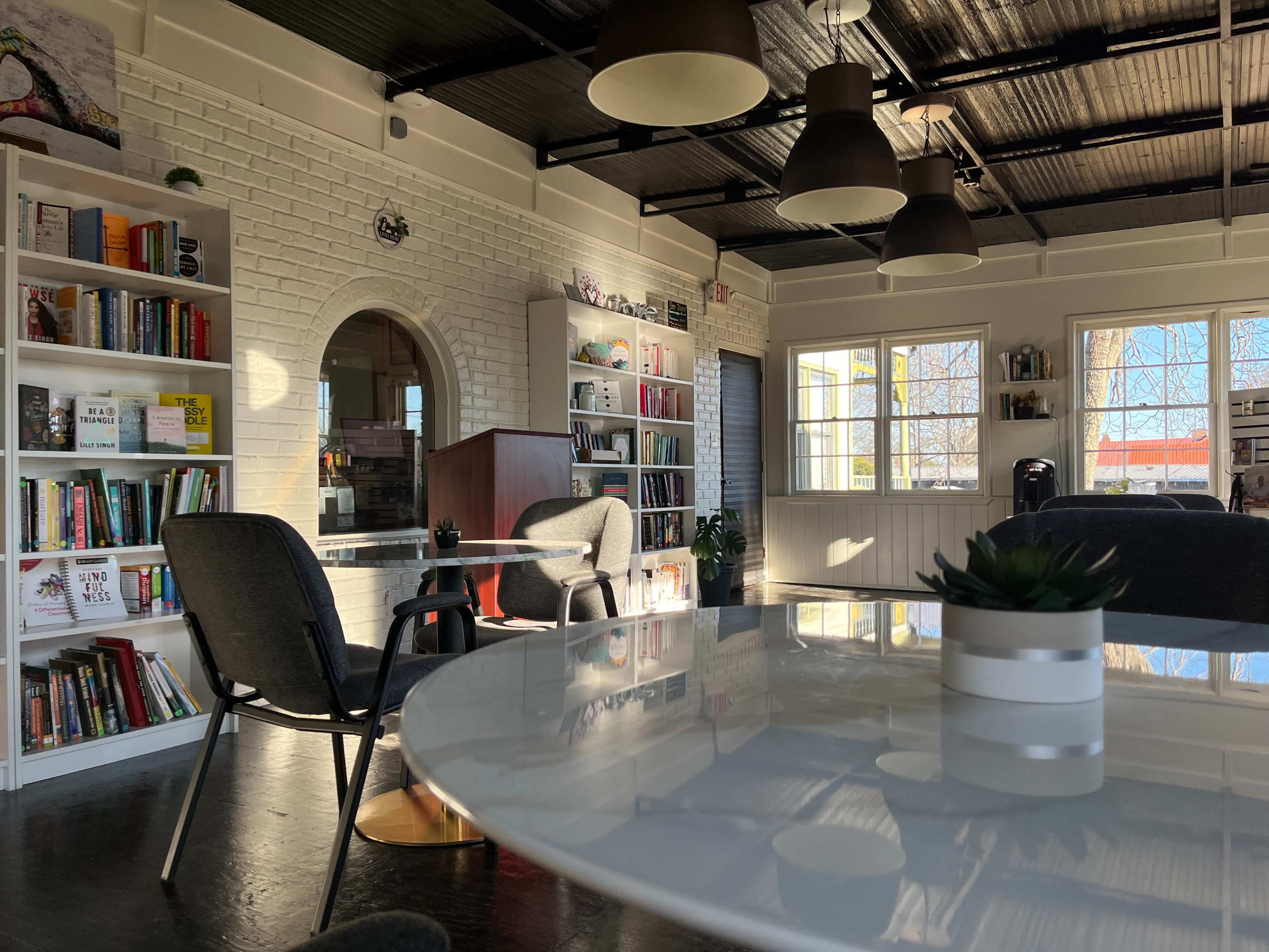 A bright, modern interior of a cozy reading or study space with bookshelves, tables, and chairs.
