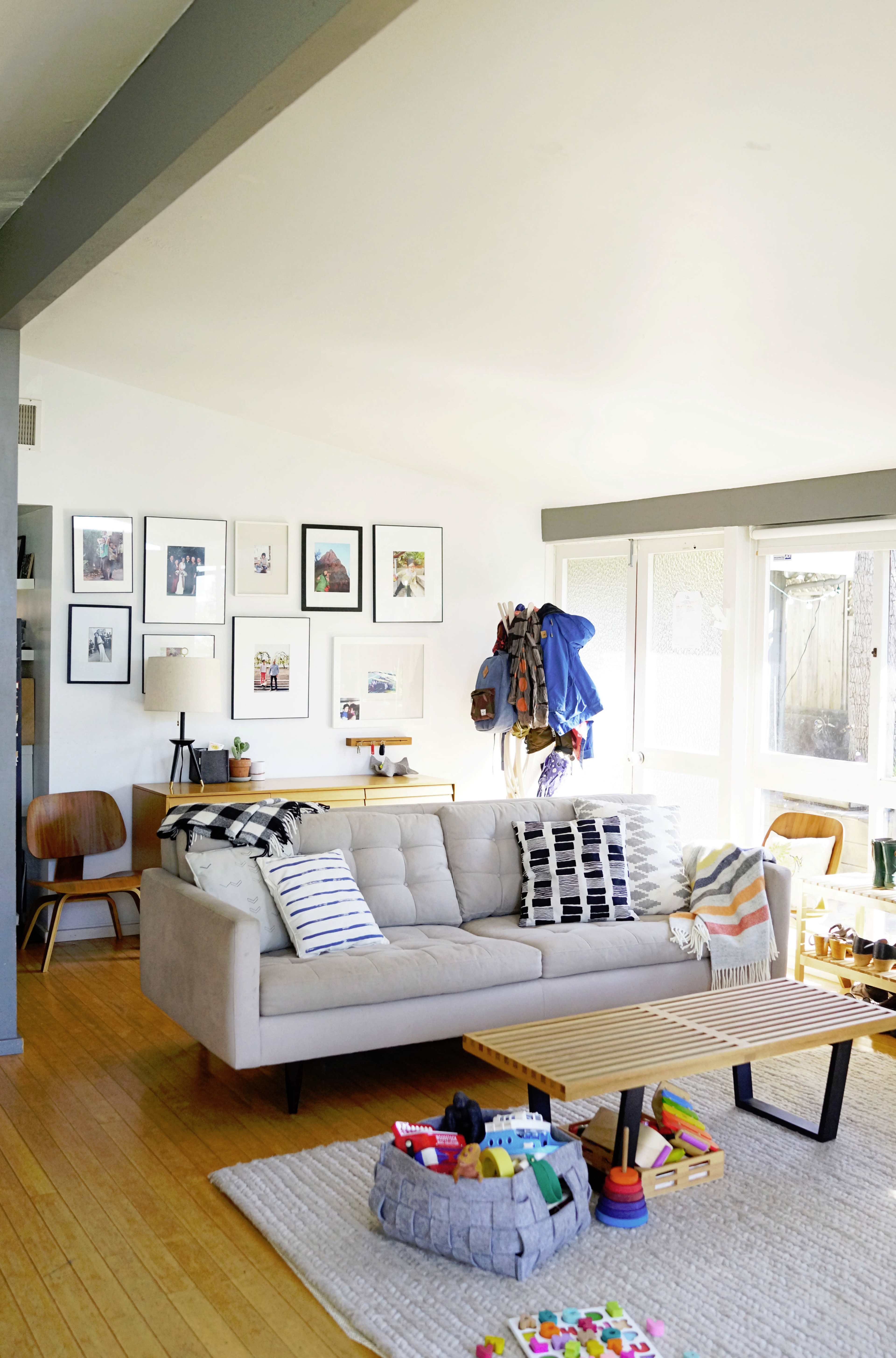 The living room features a light-colored sofa with striped cushions, a wooden coffee table, and a gallery wall of framed photos.