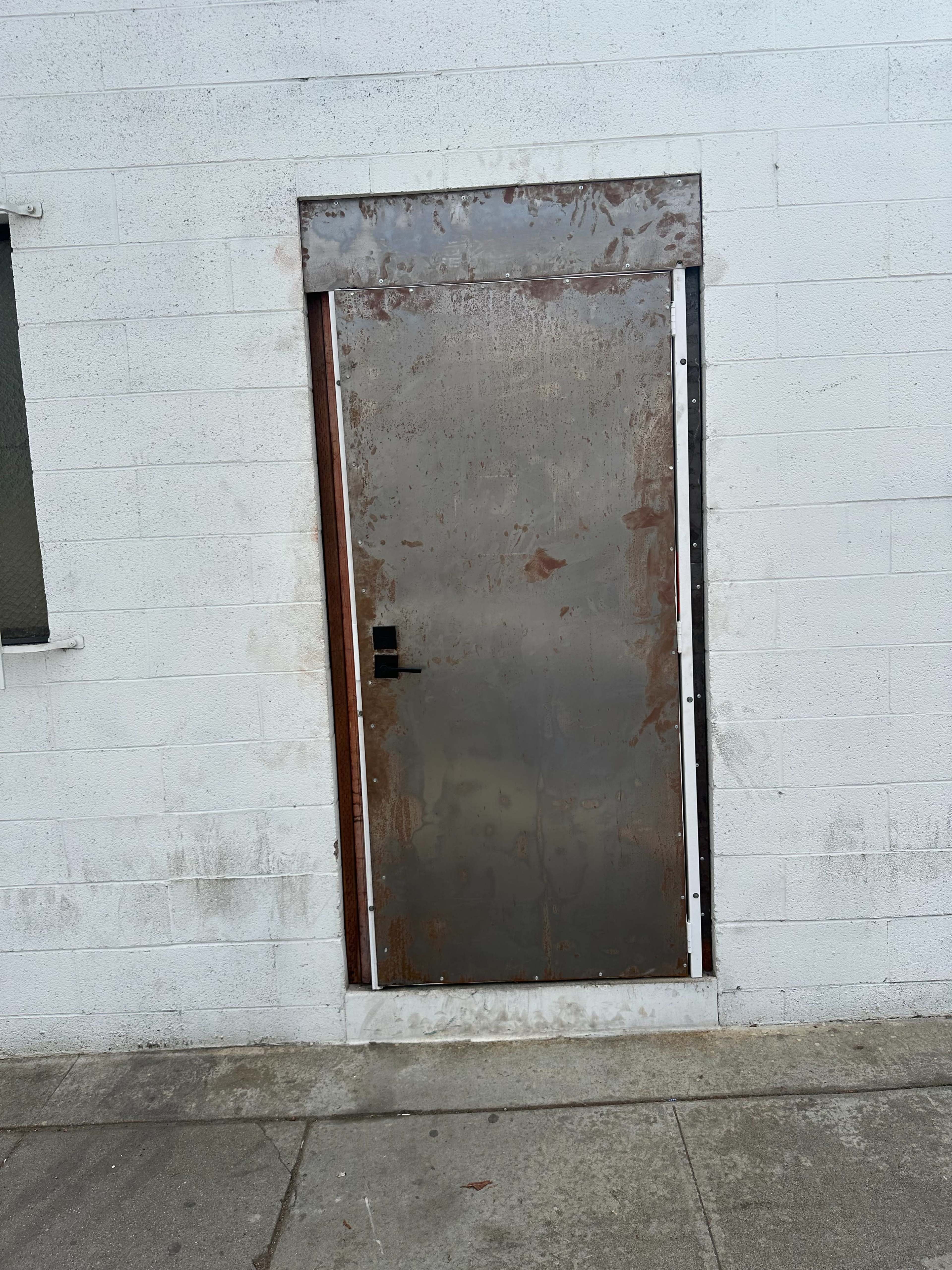 A metal door is mounted on a gray concrete wall.