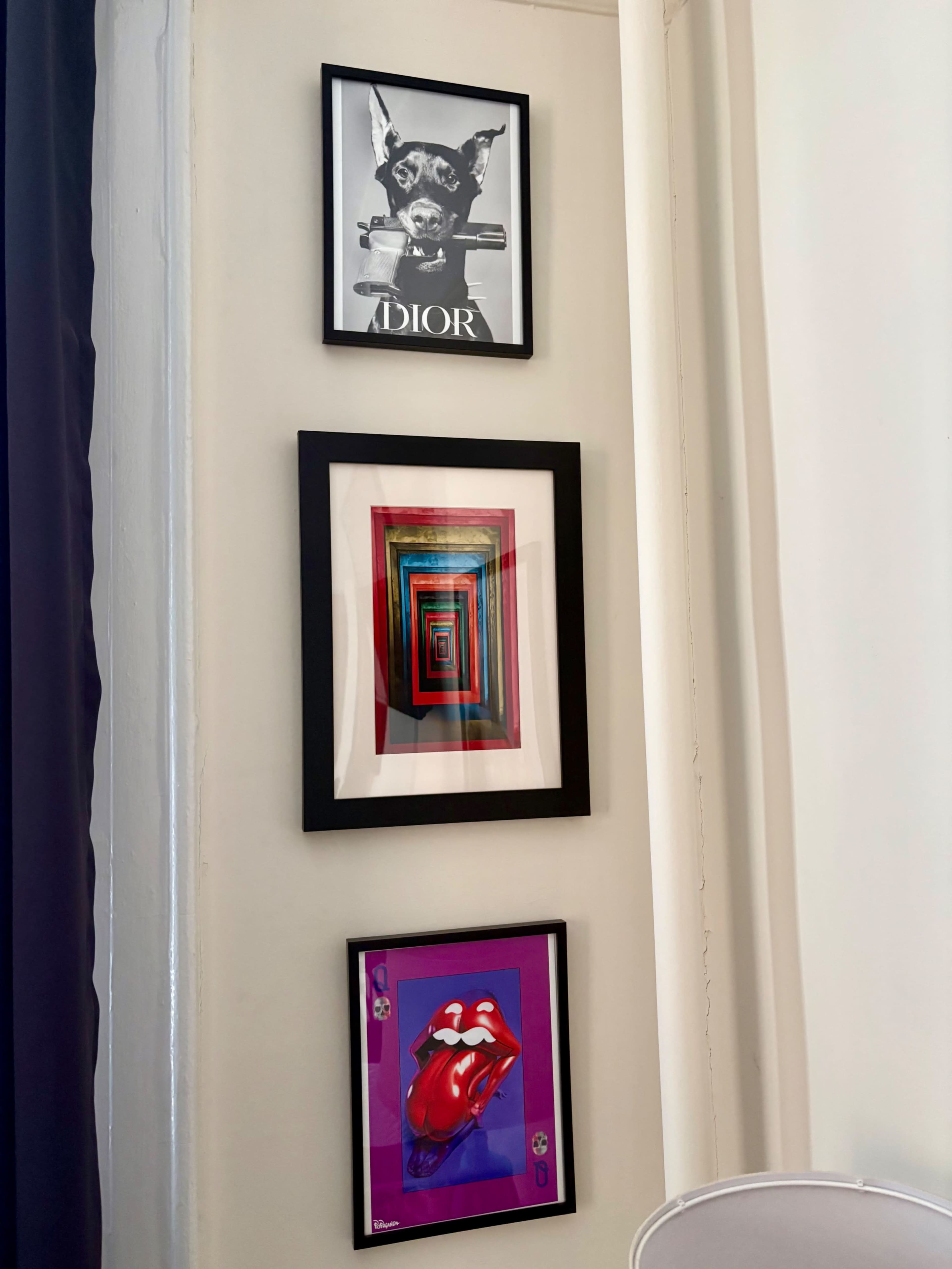 The image features three framed artworks hanging on a wall, including a dog portrait with "ADIOR" text, a colorful geometric design, and a graphic of lips.