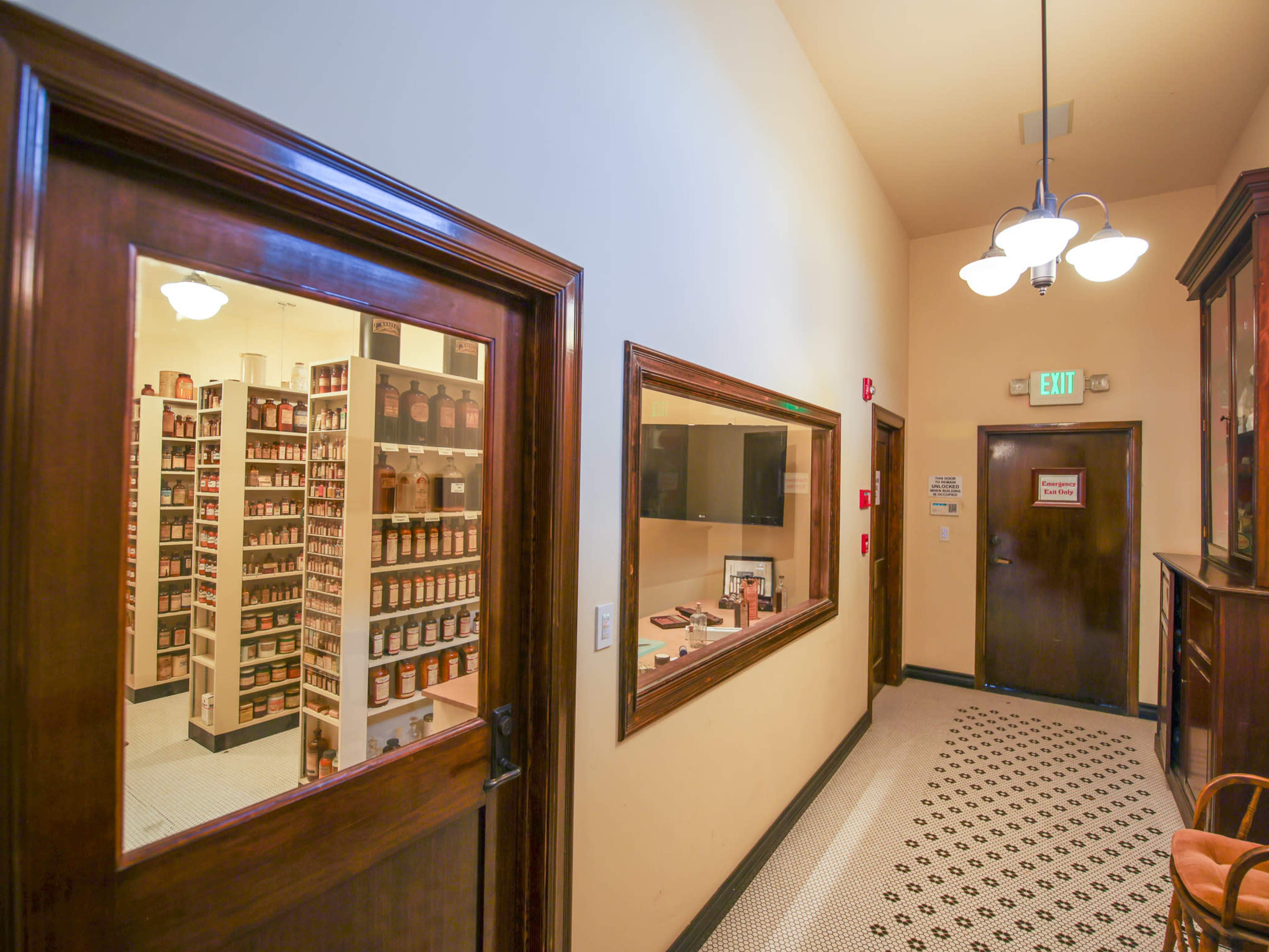 A hallway with wooden trim leading to doors and a storage area filled with neatly arranged jars on shelves.