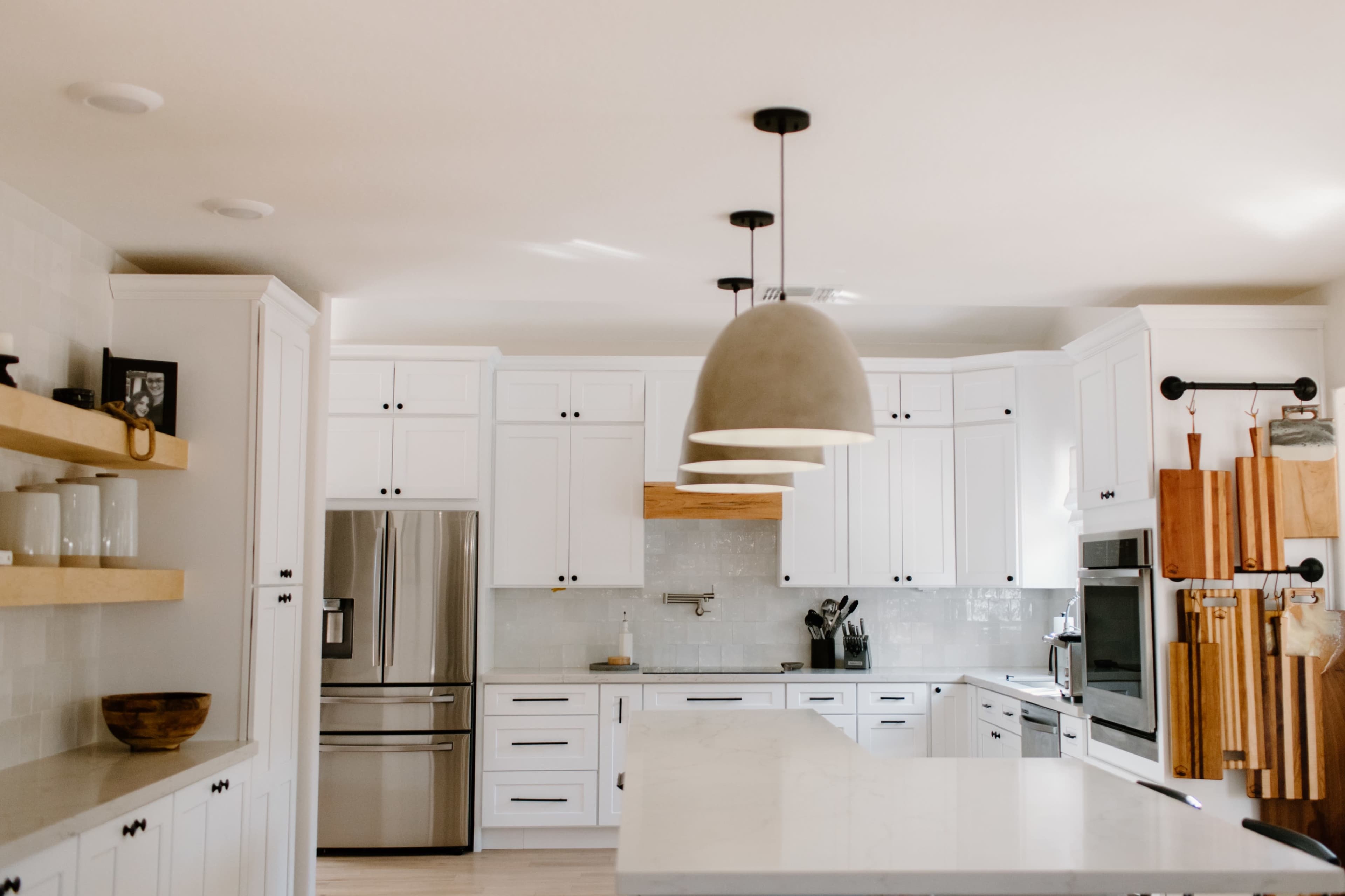 The kitchen features white cabinetry, stainless steel appliances, and a large island with a pendant light overhead.