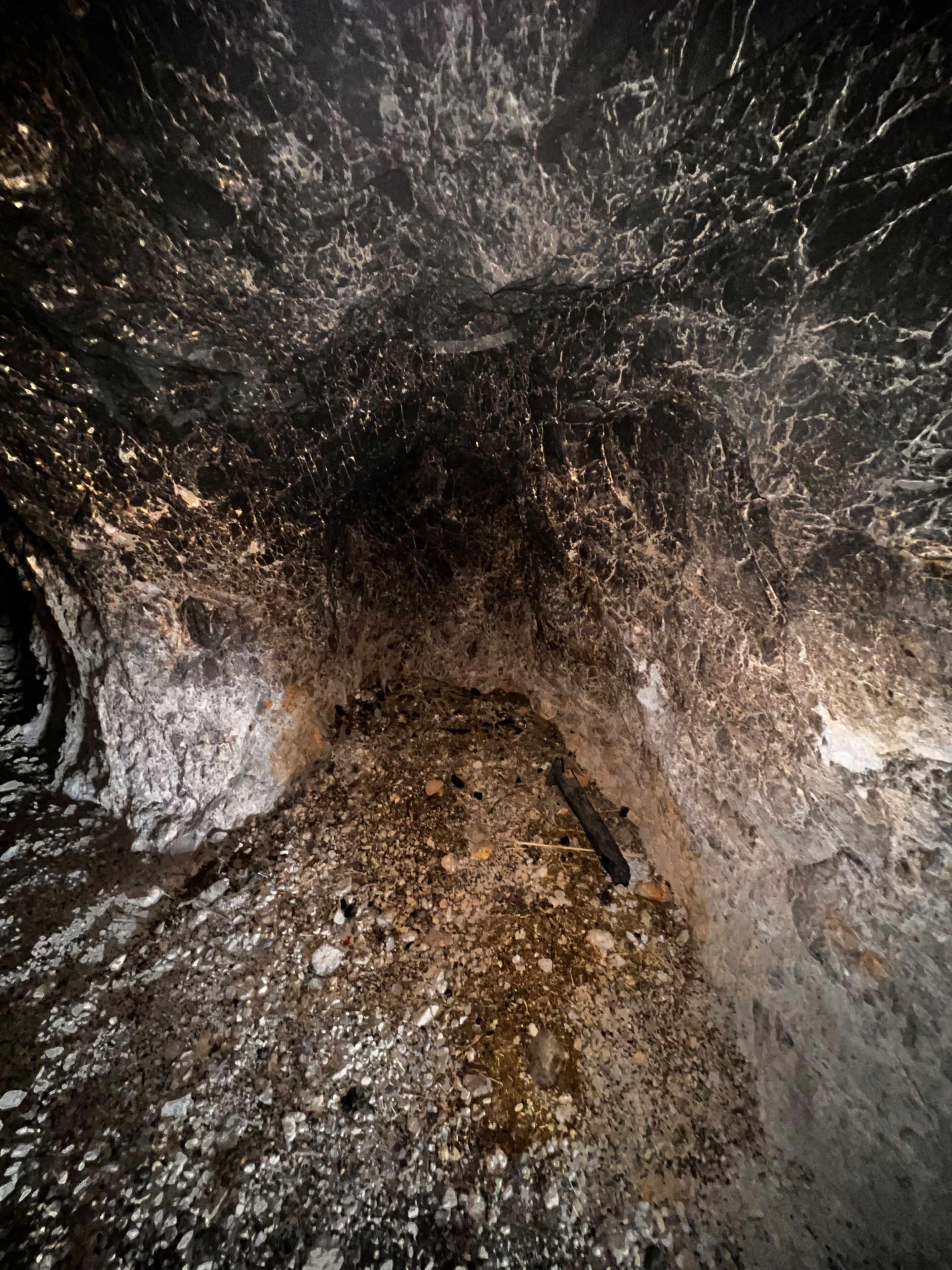 The interior of a cave with rough, rocky walls and a loose gravel floor.