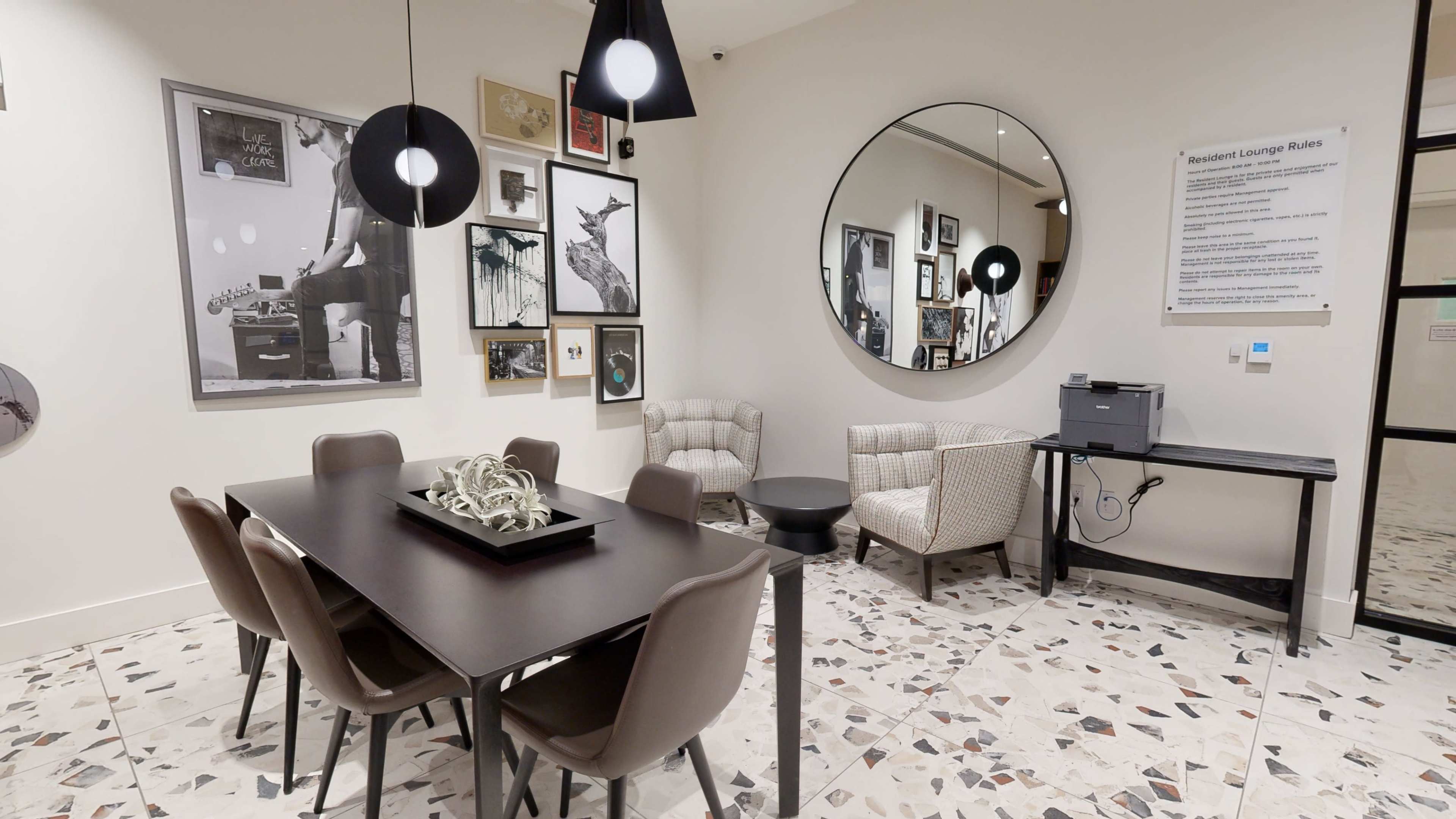 A modern lounge area features a dining table with chairs, two armchairs, a round mirror, and framed artwork on the walls.