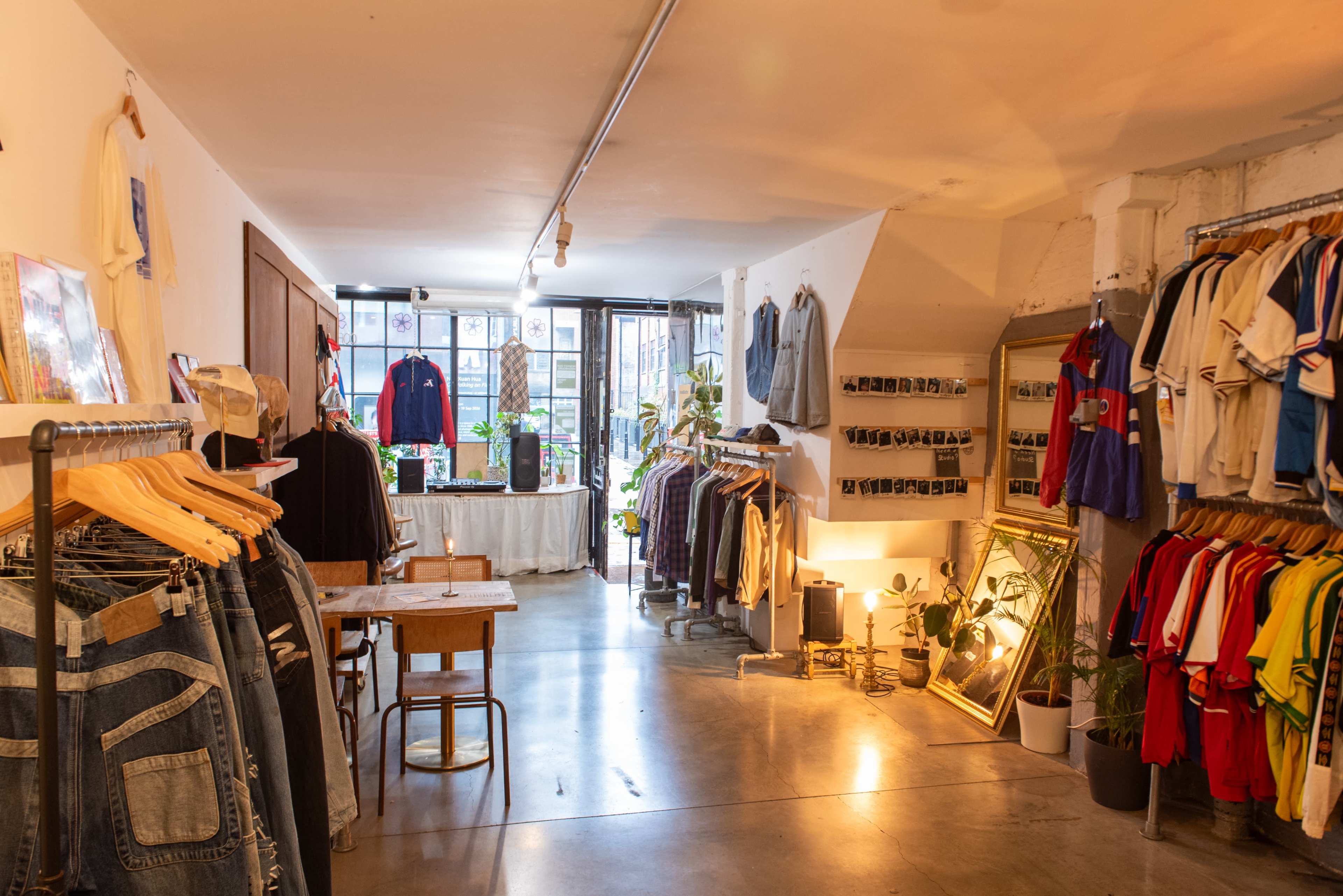 The image shows a clothing store with racks of various apparel, a table, and large windows providing natural light.