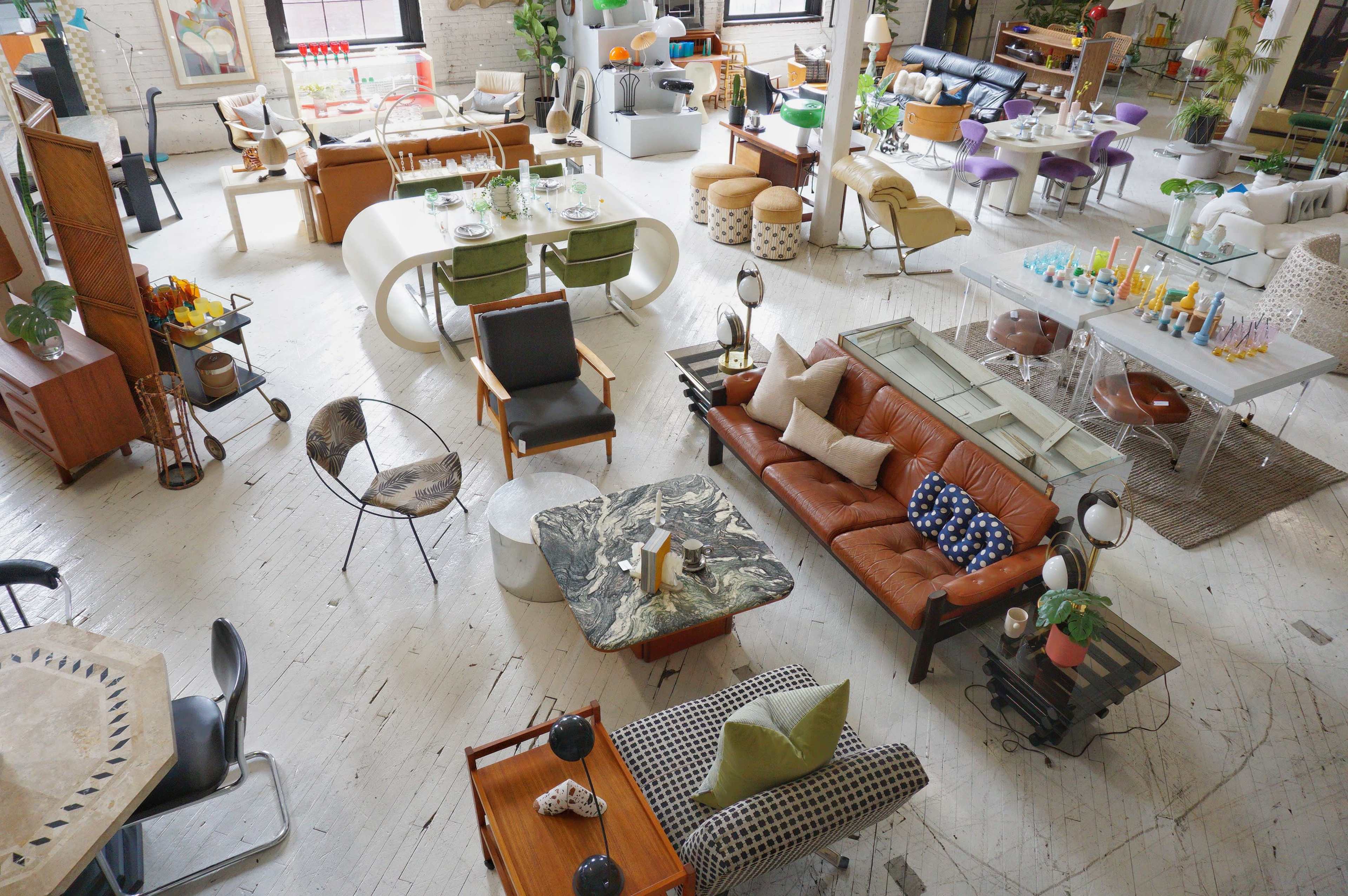An interior space filled with various pieces of modern furniture, including seating, tables, and decorative items, arranged in an open layout.