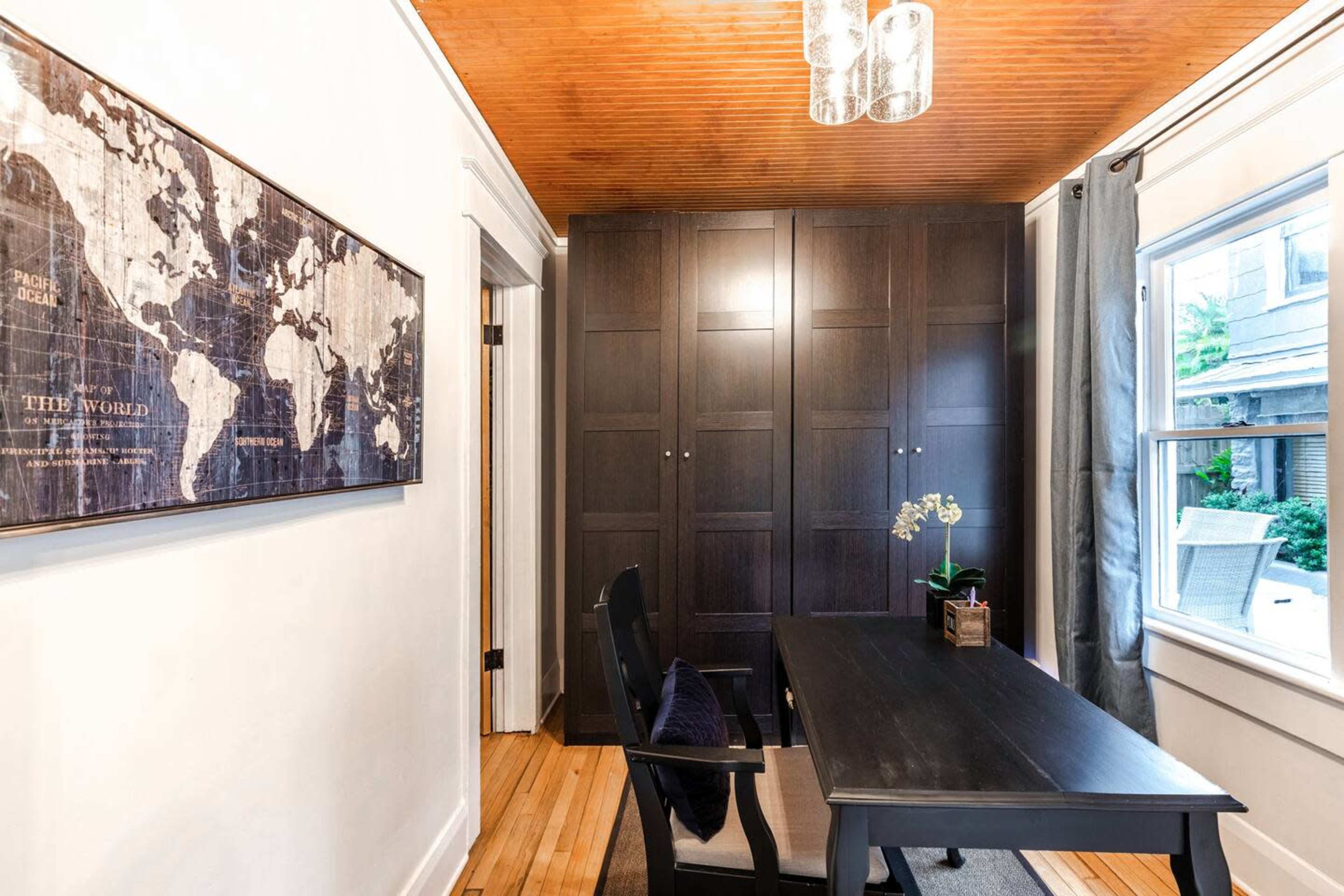 A small office space with a dark wooden desk, a world map on the wall, and a closet with closed doors.