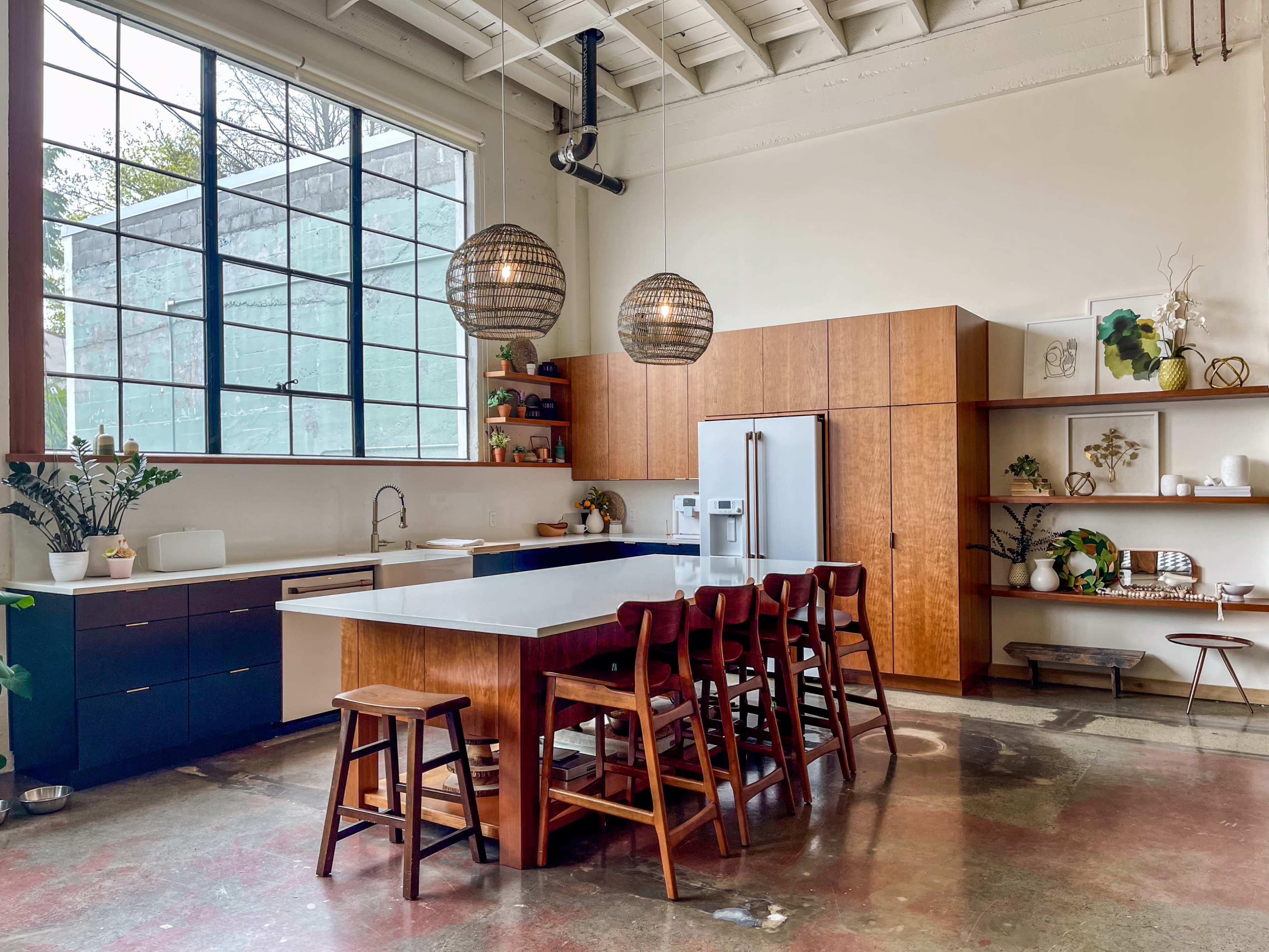 The kitchen features a large island with seating, modern appliances, and a combination of wooden cabinetry and open shelving.