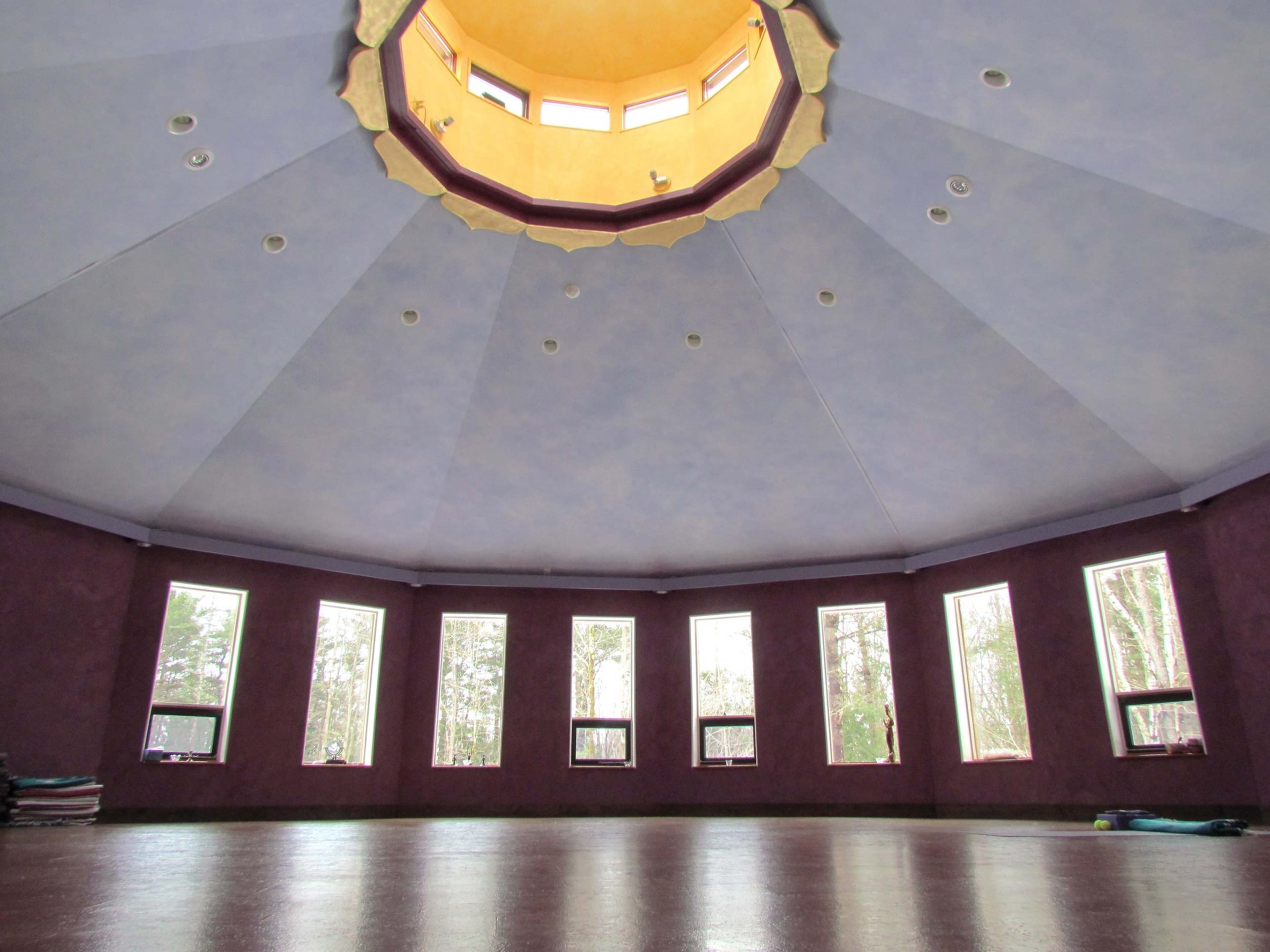 The interior of a circular room with a domed ceiling and multiple windows around the walls.