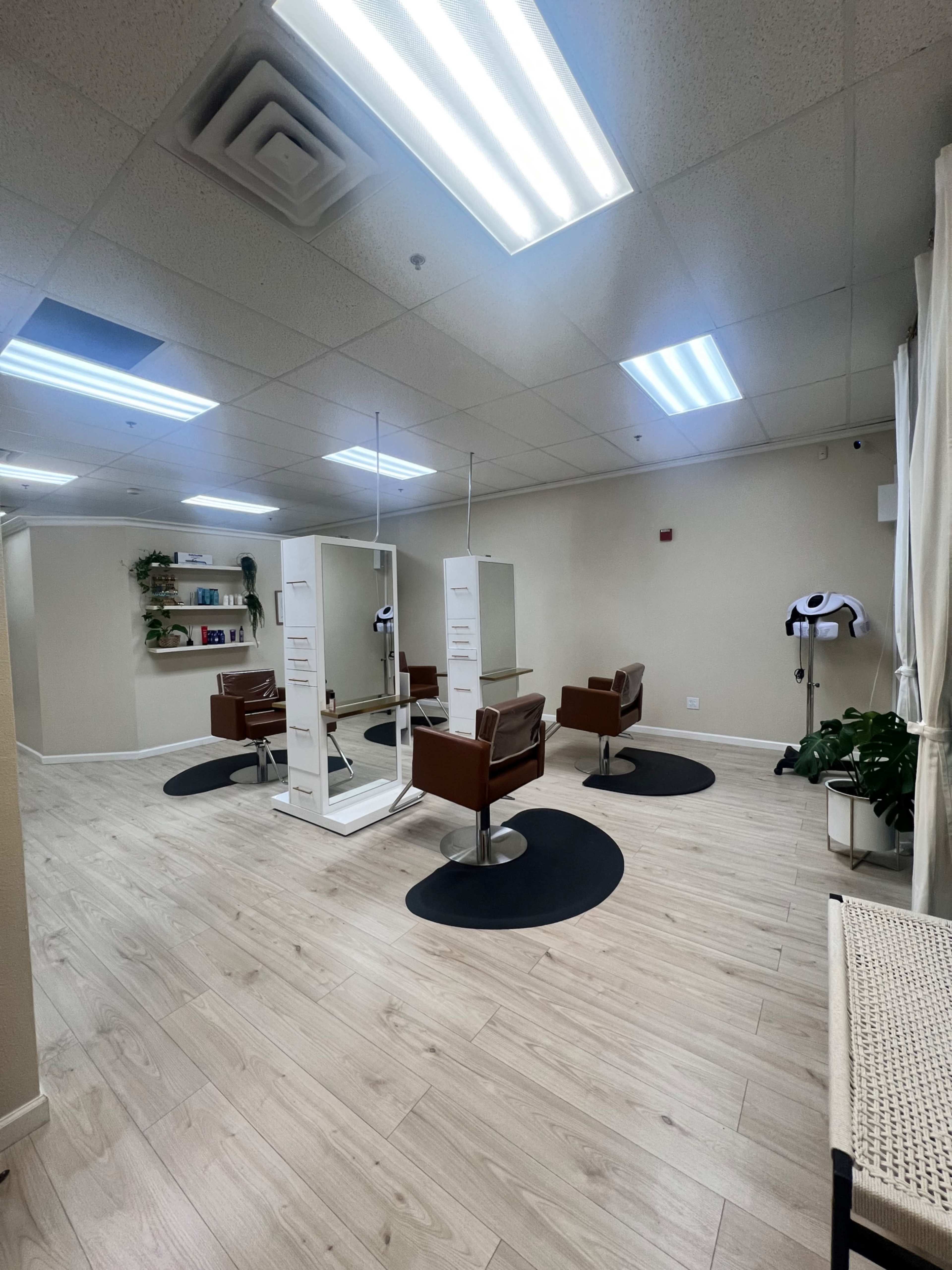 A spacious hair salon featuring three styling chairs, mirrors, and a small waiting area.