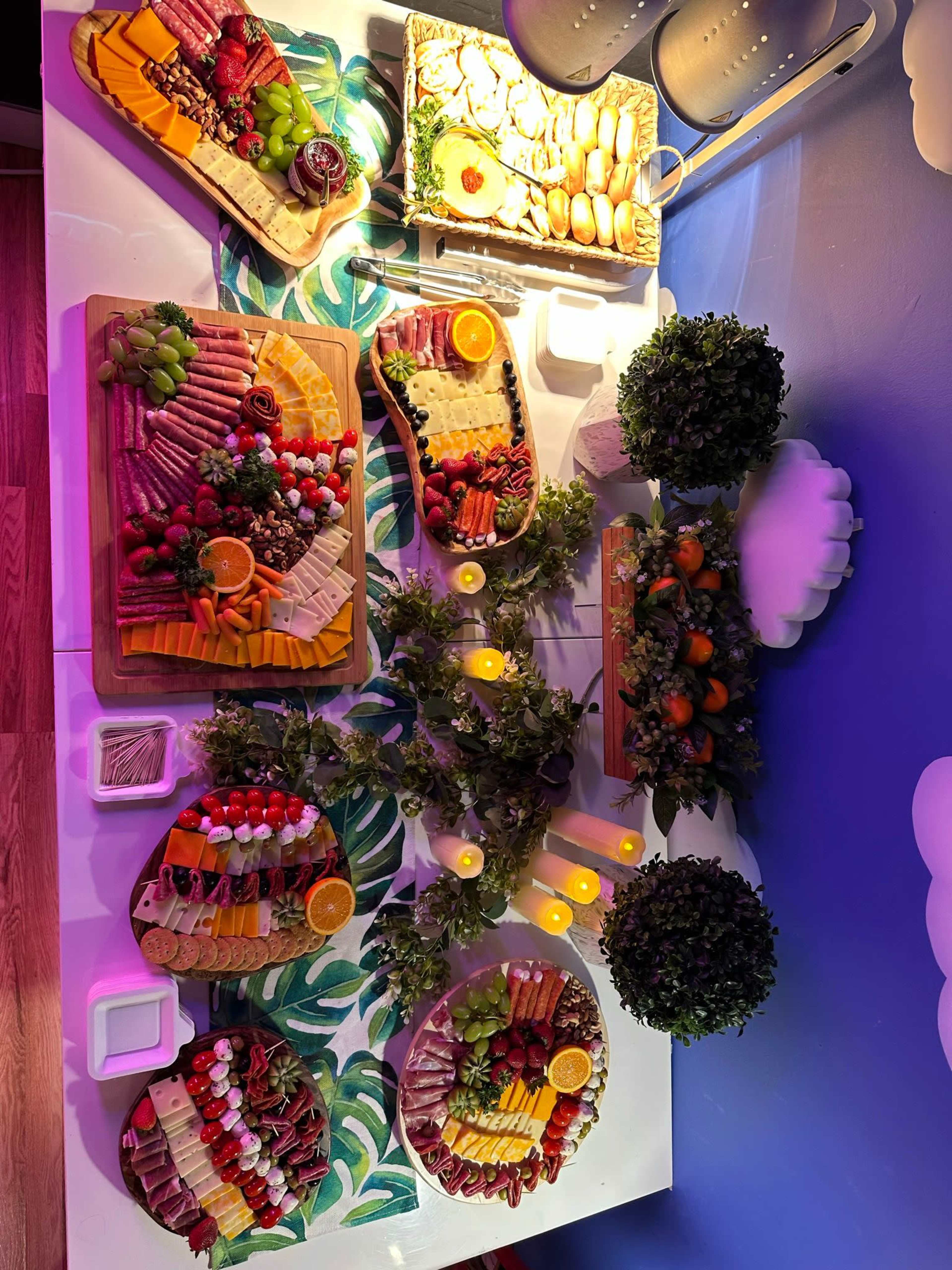 The image shows a vibrant spread of various charcuterie boards featuring cheeses, fruits, meats, and garnishes arranged elegantly on a table with decorative elements.