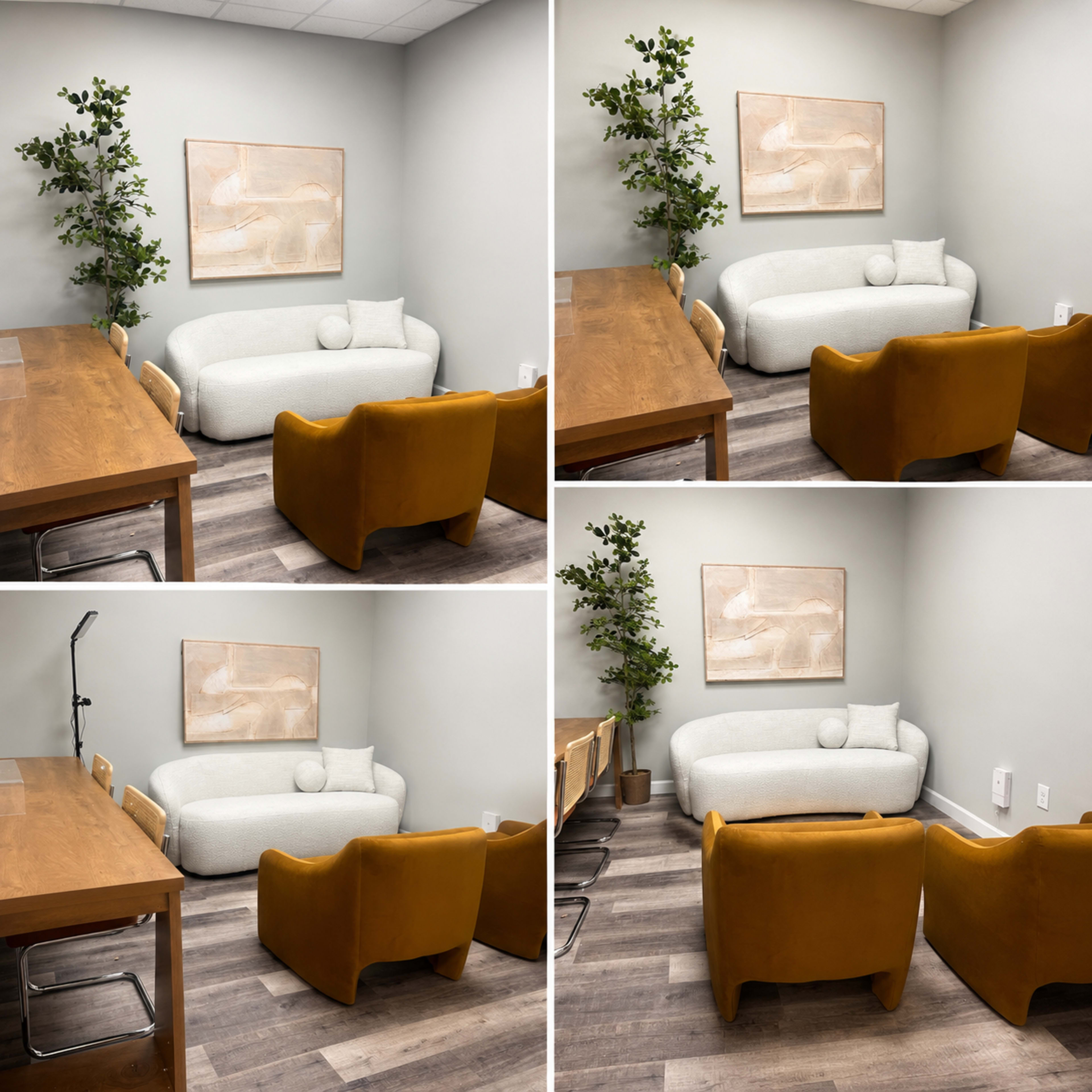 The image shows a small meeting room featuring a light-colored couch, two mustard yellow chairs, a wooden table, and a decorative plant against a gray wall.