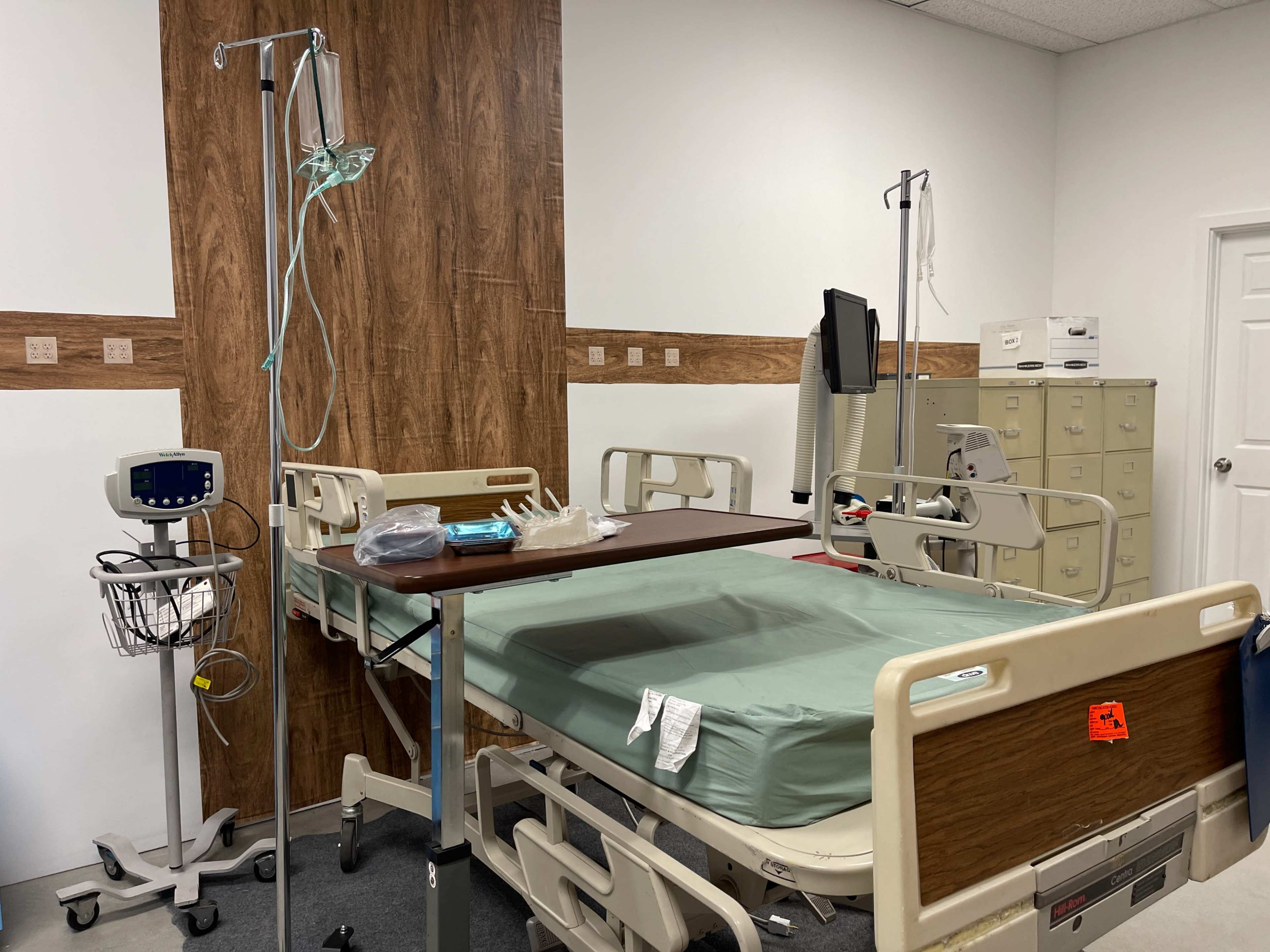 A hospital room with a bed, medical equipment, and a privacy curtain.