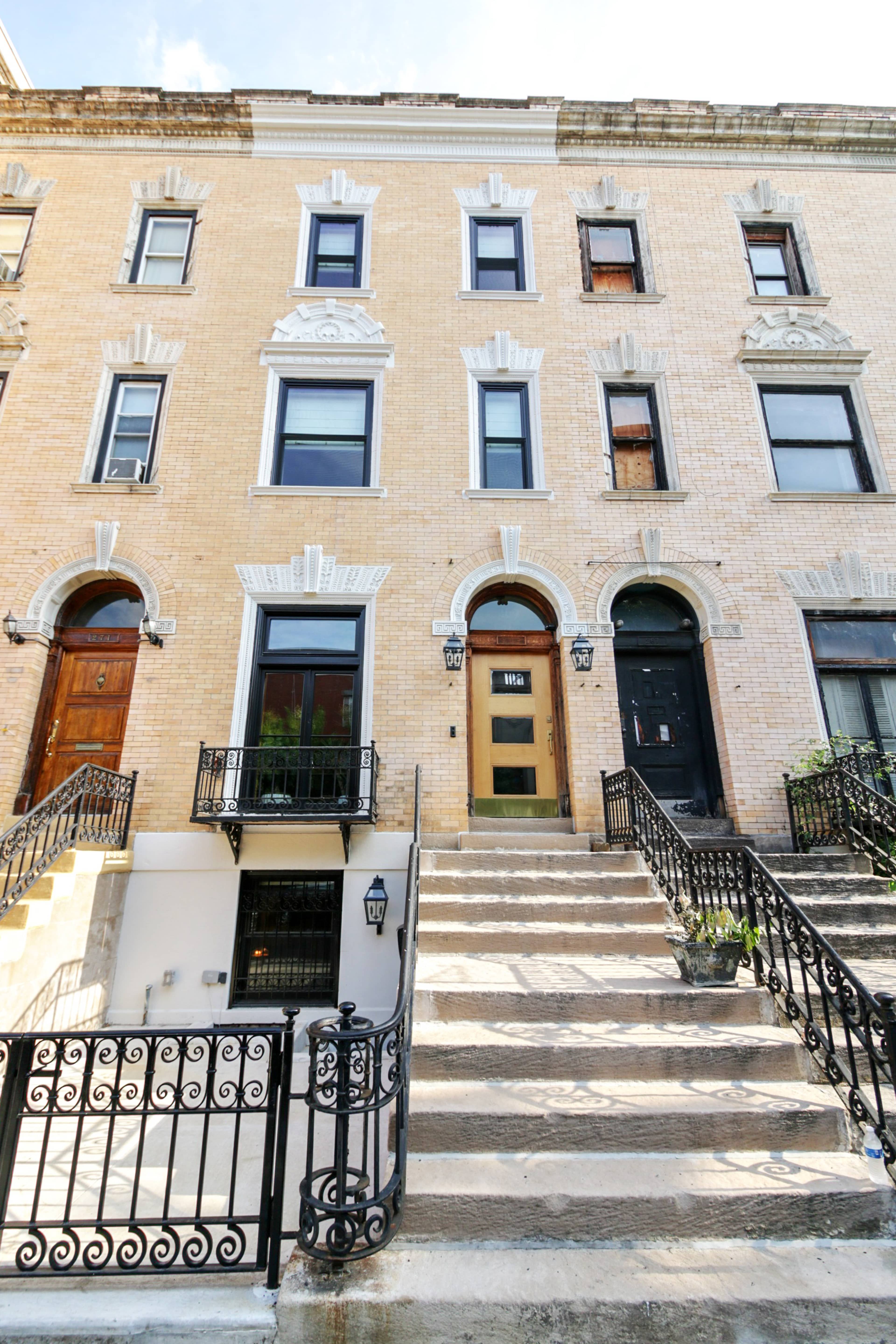 A row of three brick townhouses with a set of stairs leading to the front entrances.
