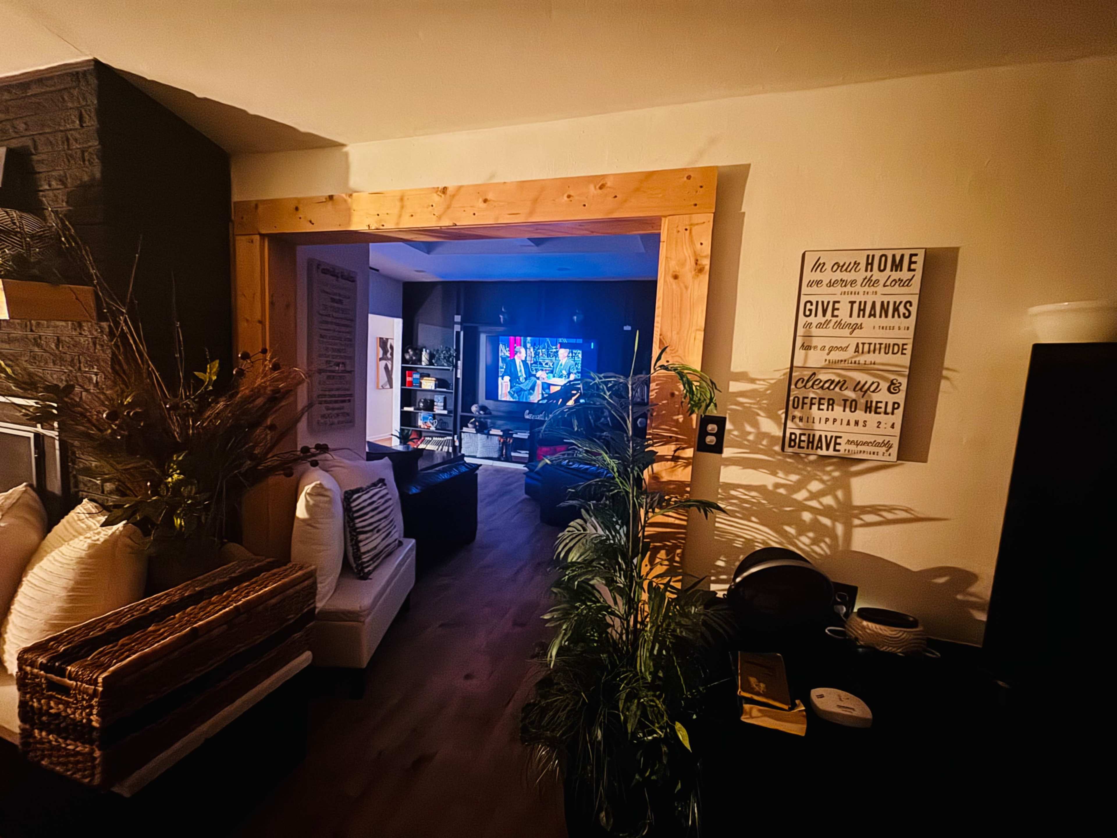 The image shows a cozy interior space with a welcoming entryway leading to a living area where a television is visible.