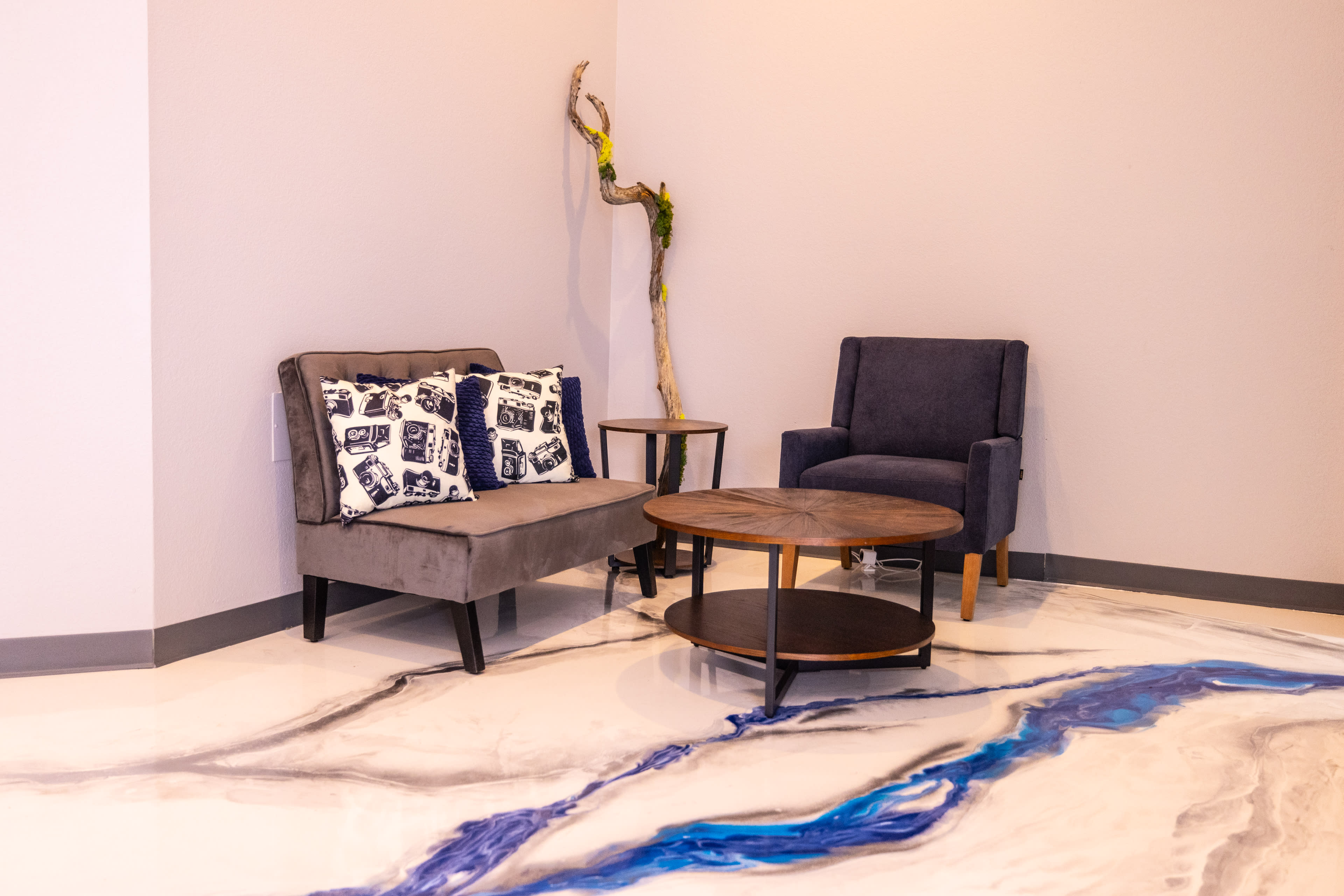 A small seating area features two armchairs and a coffee table on a patterned floor with a blue resin design.