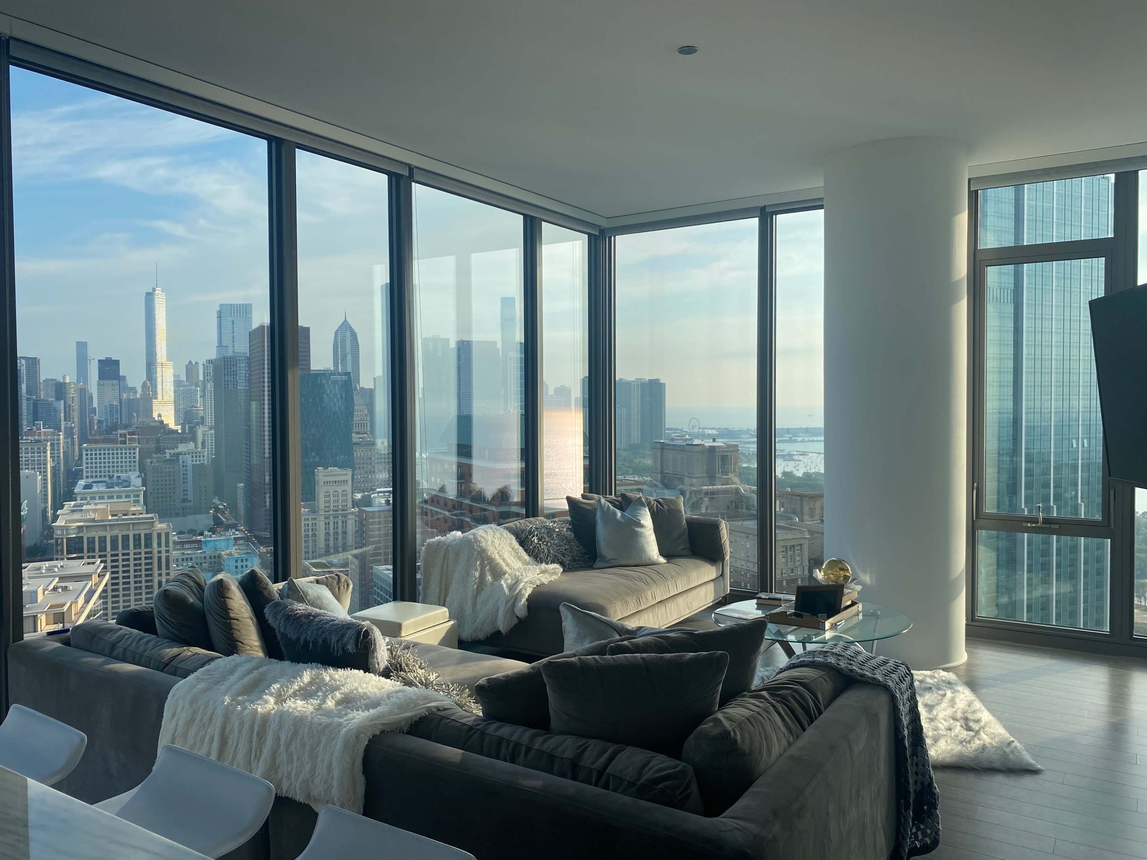 A modern living room features large windows with a city skyline view and contemporary furniture.
