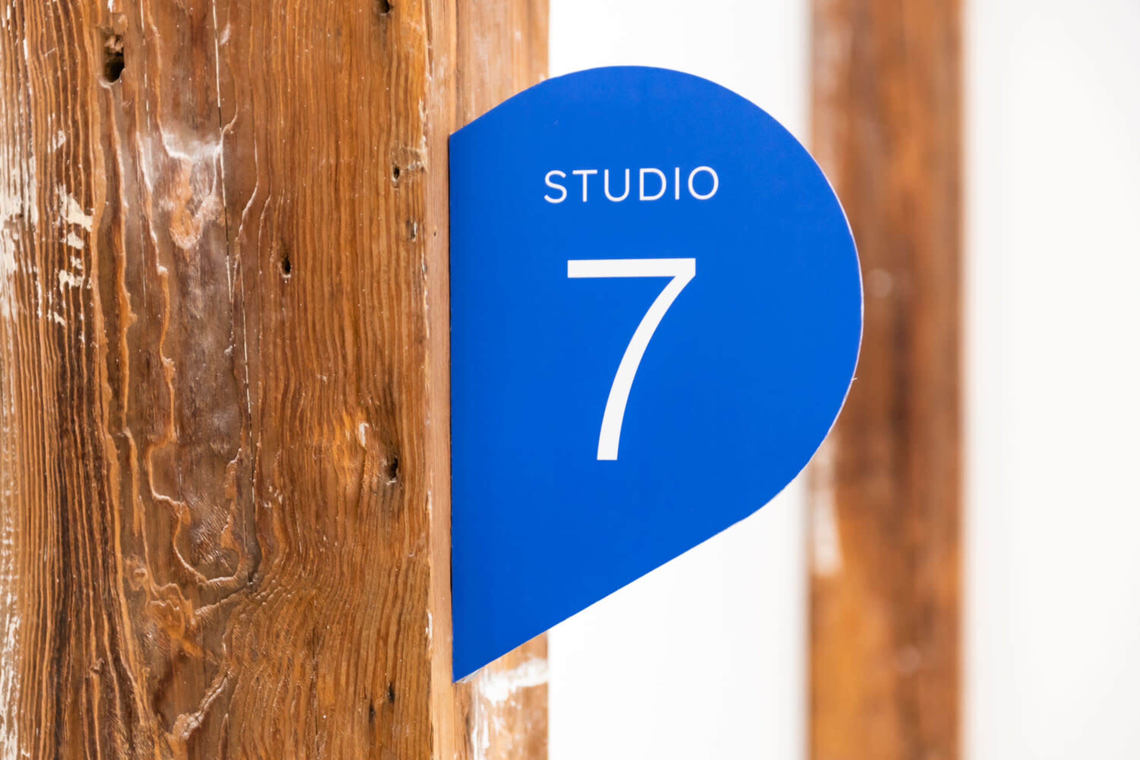A blue sign displaying the number "7" is attached to a wooden post, indicating a studio room.