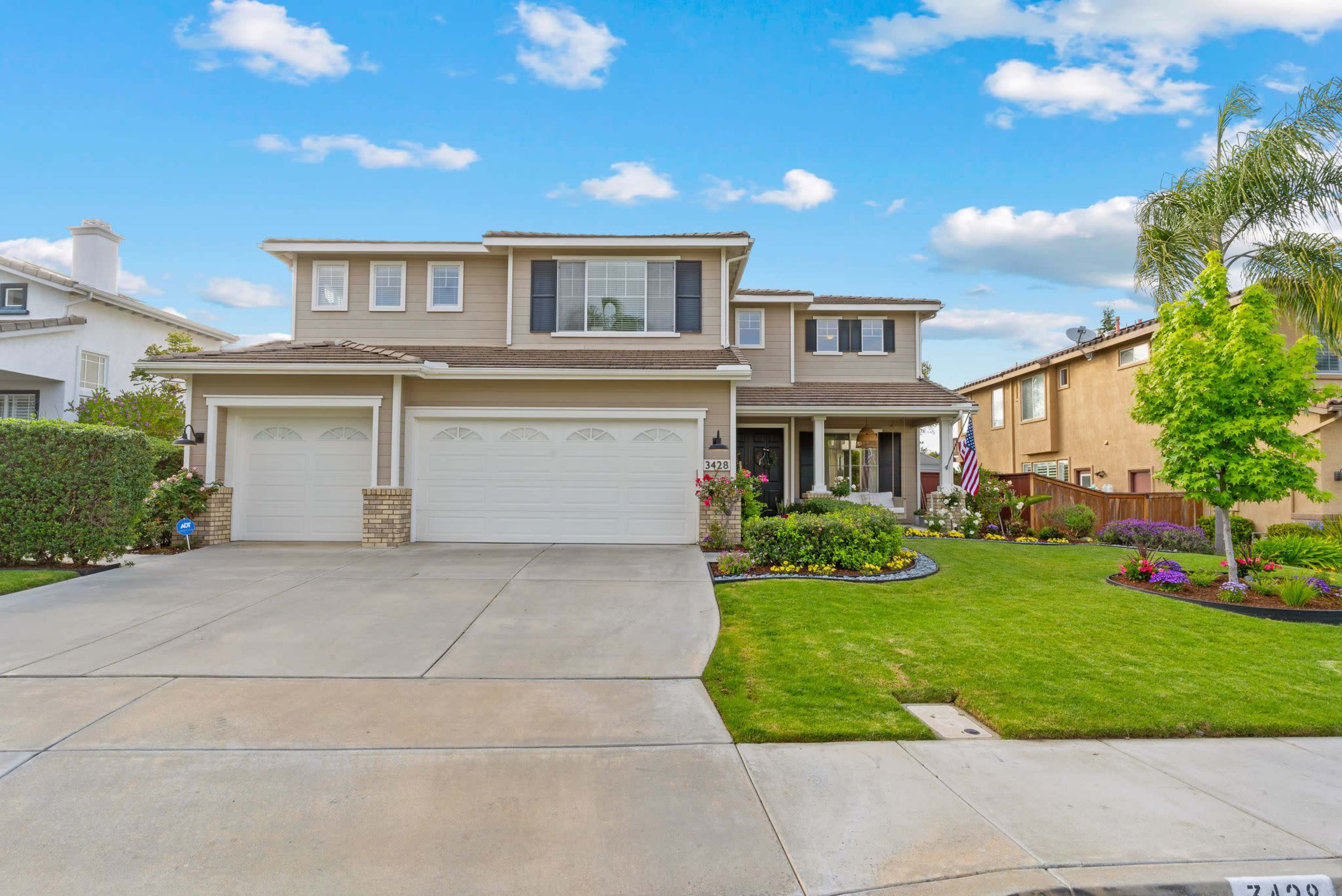 A two-story suburban home with a well-maintained lawn and a double garage.