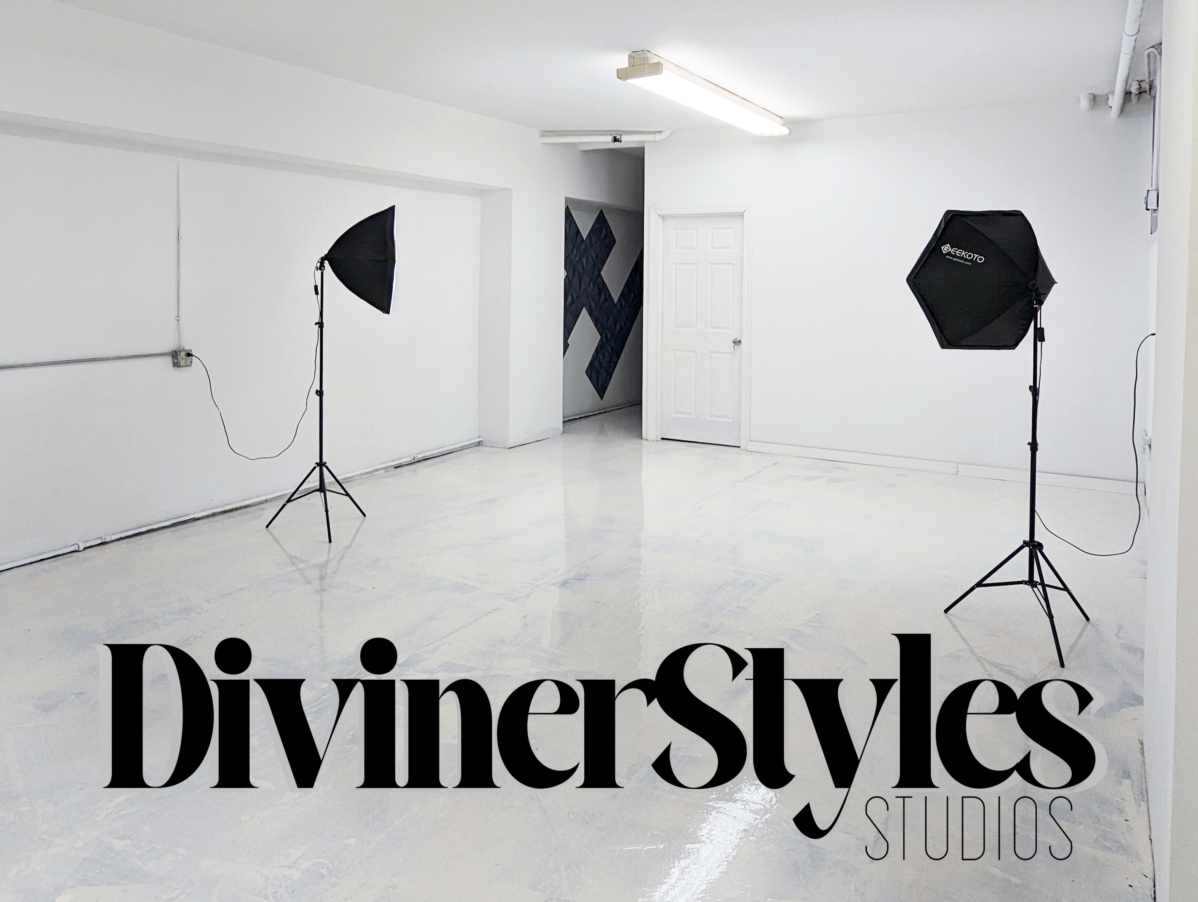 A spacious studio with two softbox lighting setups and a plain white wall.