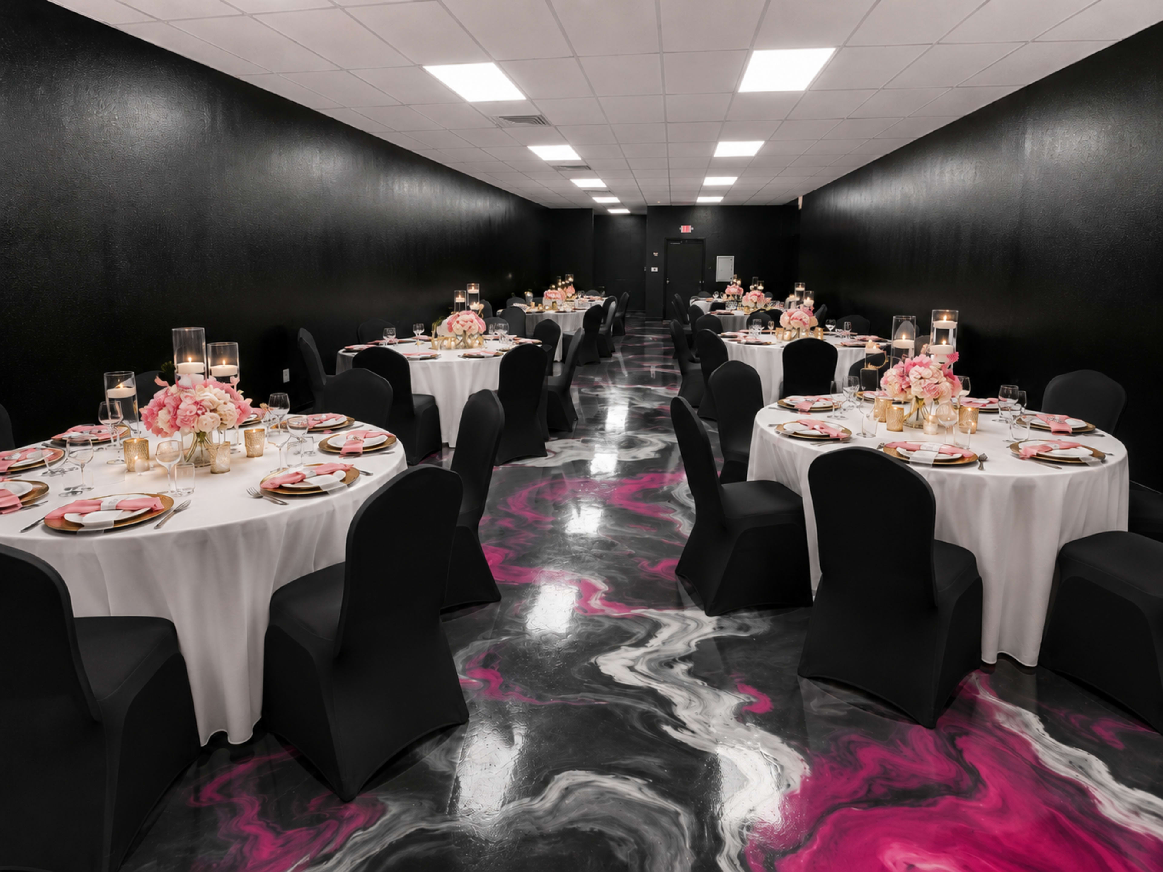 The image shows a banquet hall with black walls and glossy, marbled flooring, featuring several round tables set with white tablecloths, black chairs, and floral centerpieces.