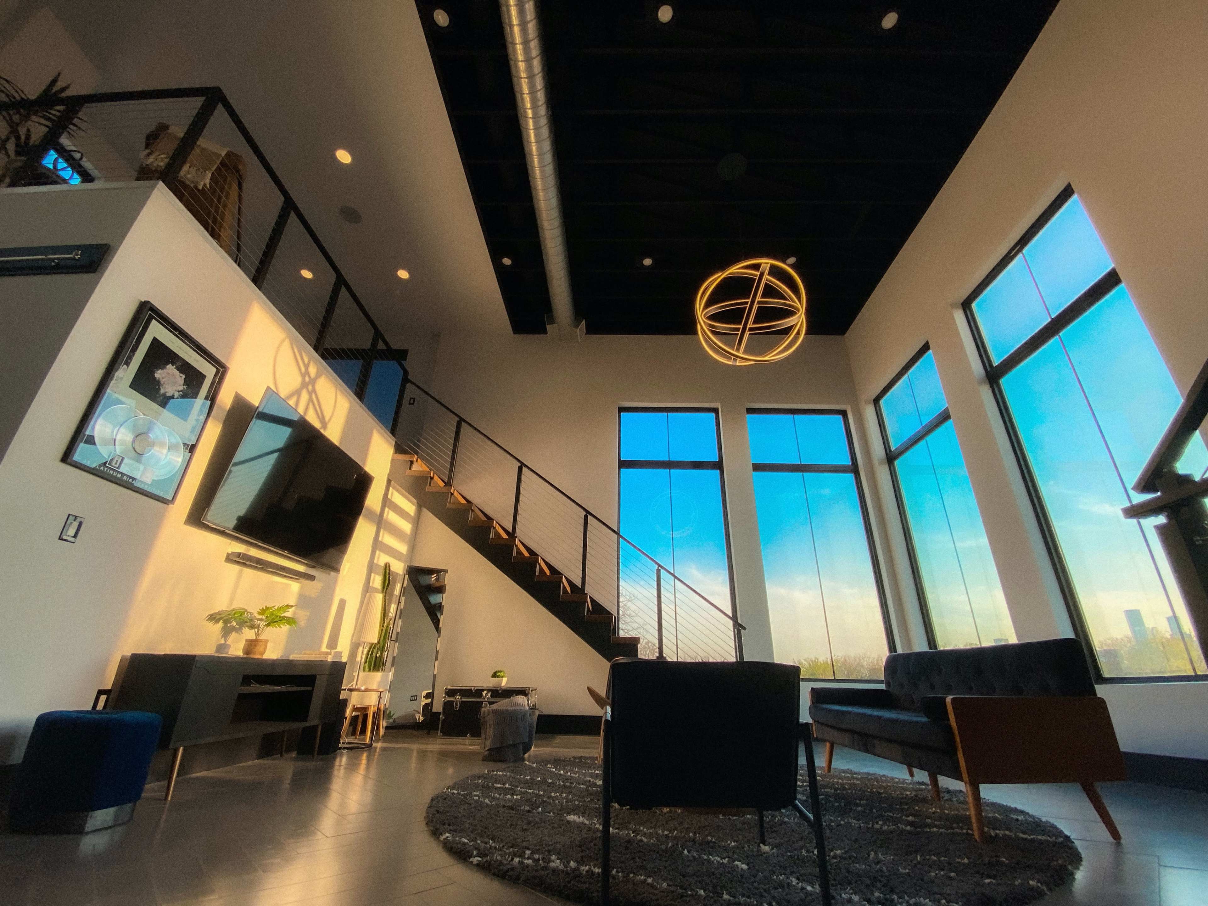 A modern living room features large windows, a spiral staircase, and contemporary furniture.