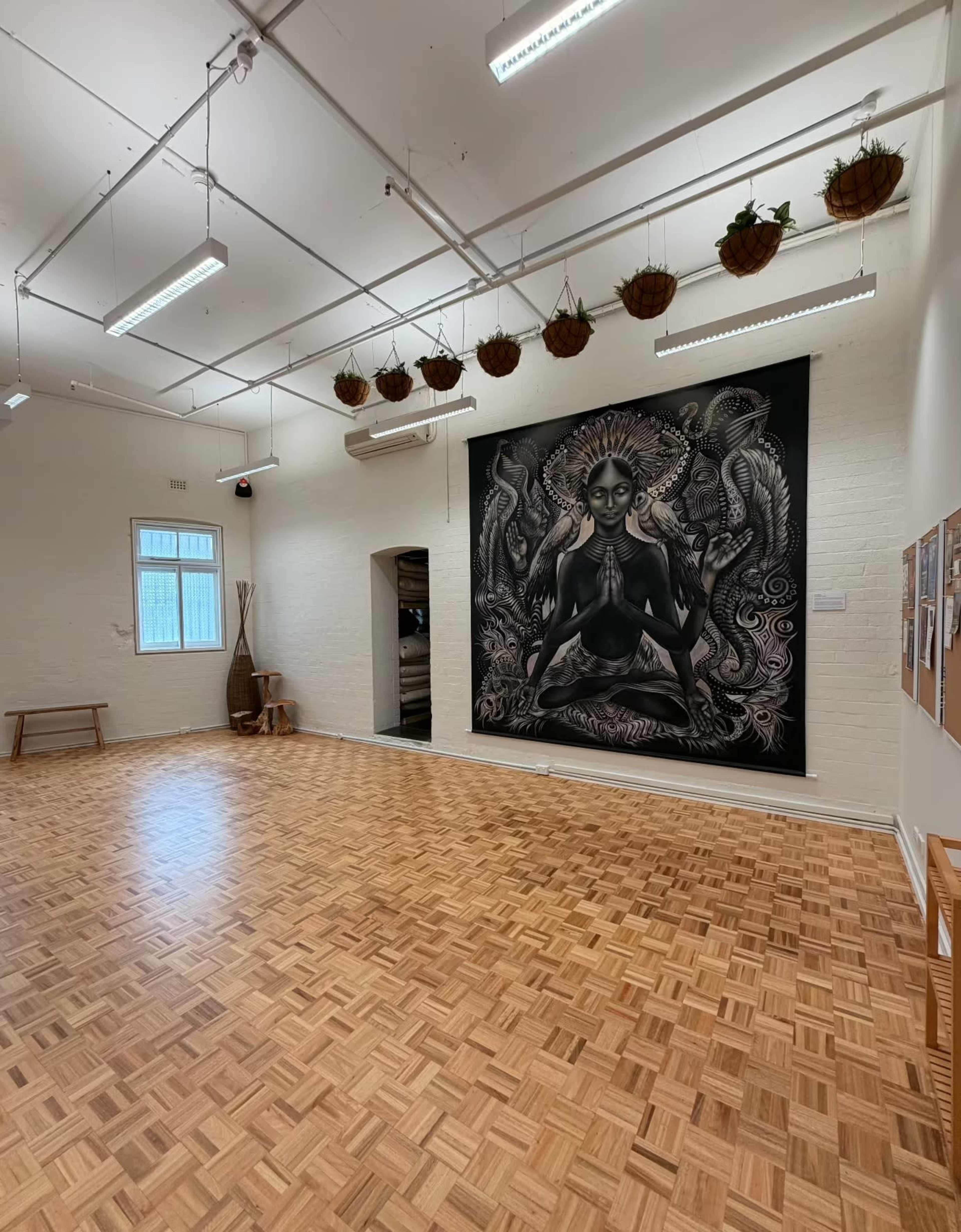 The room features a wooden floor with a large mural of a seated figure in a meditative pose on the wall.
