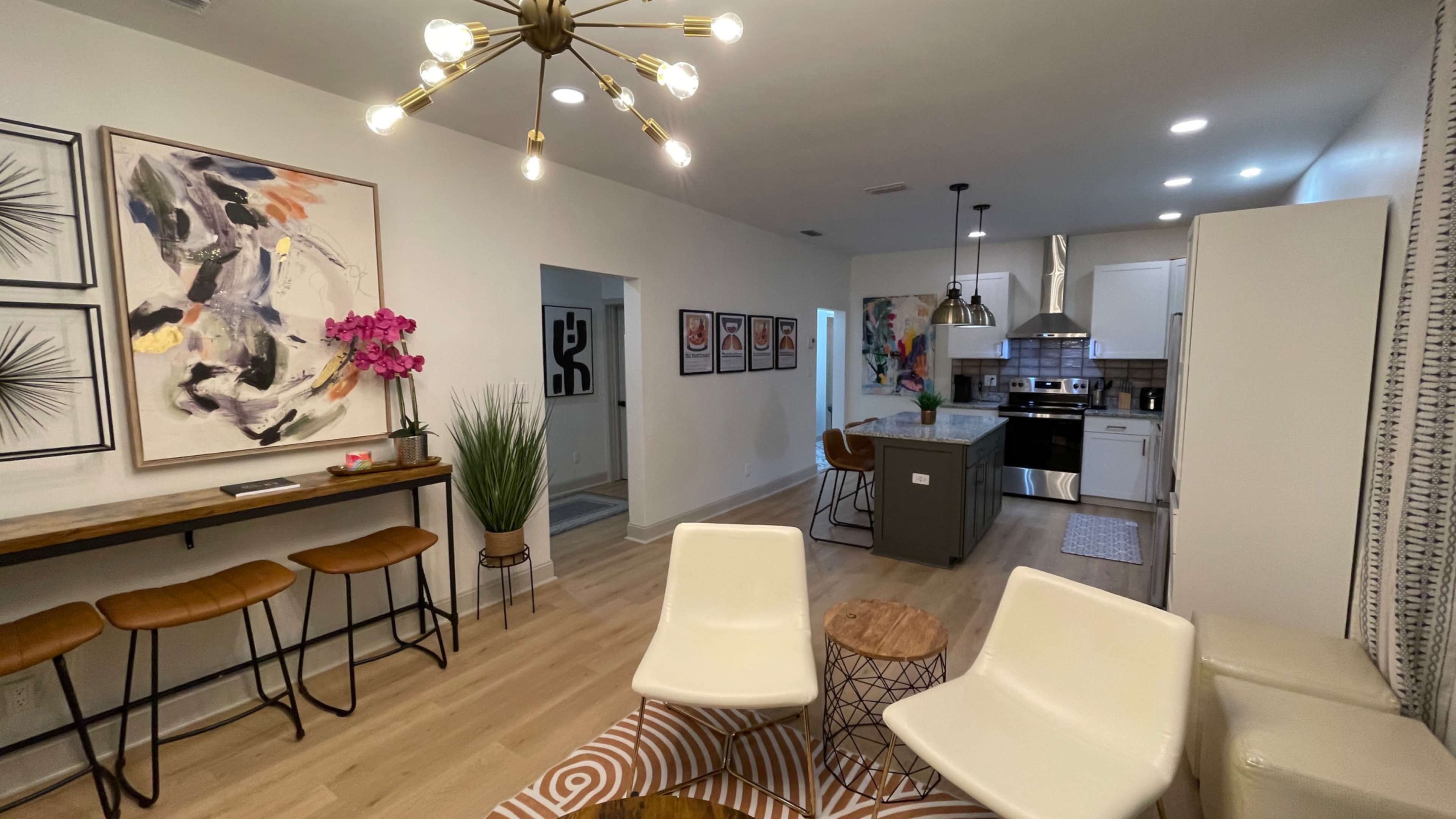 A modern open-concept living space featuring a kitchen with stainless steel appliances, a dining area, and stylish seating arrangements.