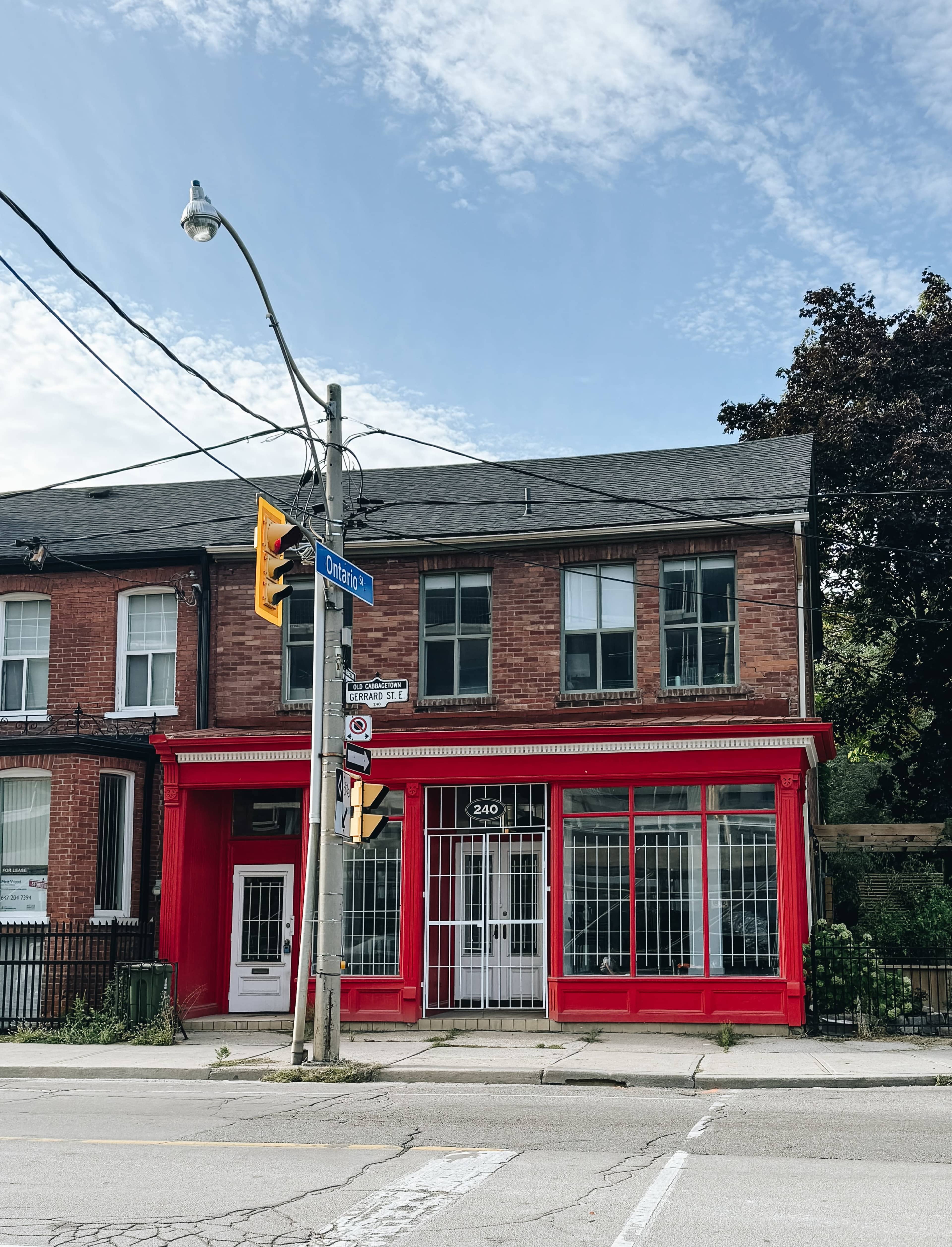 The image shows a red storefront located at the corner of a street with a traffic light and a street sign labeled "Orleans."